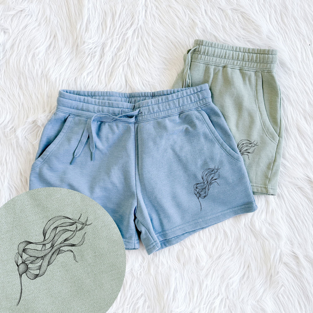 Two pairs of Cali Wave shorts in different colors printed with a black ink line drawing of a strand of bull kelp with long flowing blades, with a close-up of the print.