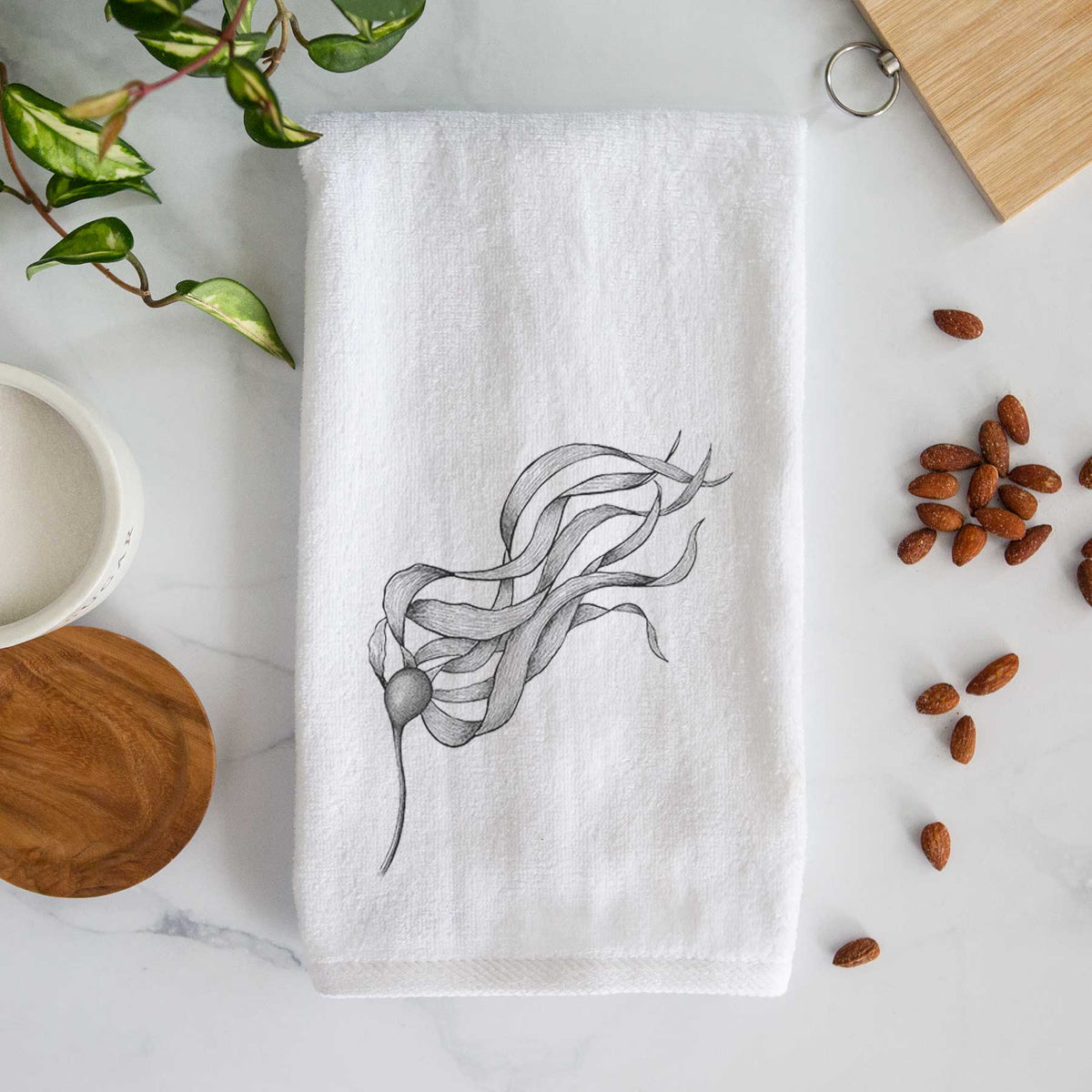 White hand towel printed with a black ink line drawing of a strand of bull kelp with long flowing blades.