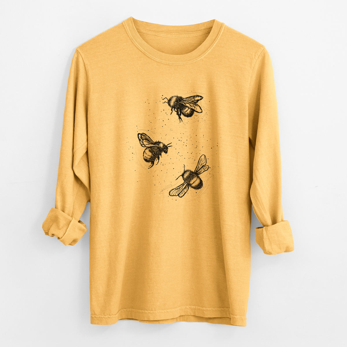Golden wheat yellow Comfort Colors long sleeve shirt laid flat with the cuffs rolled, printed with a black ink illustration of three bumble bees flying.