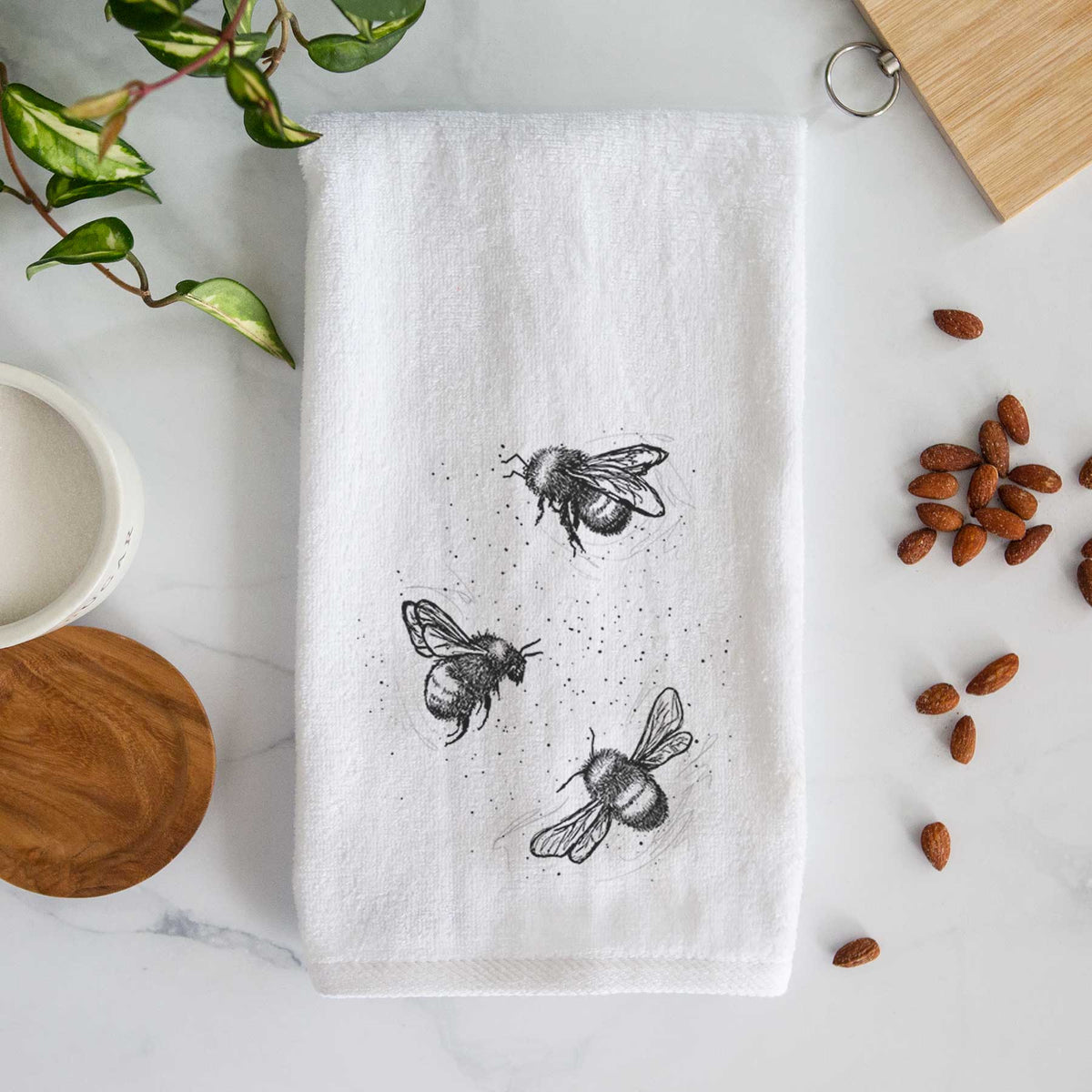 White hand towel printed with a black ink illustration of three bumble bees flying.
