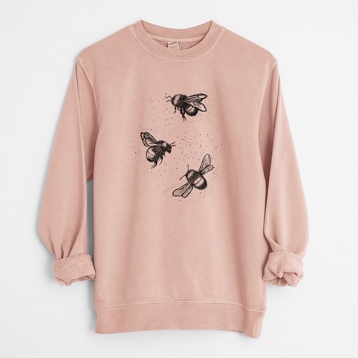 Dusty pink pigment dyed crewneck sweatshirt laid flat with the sleeves rolled, printed with a black ink illustration of three bumble bees flying.