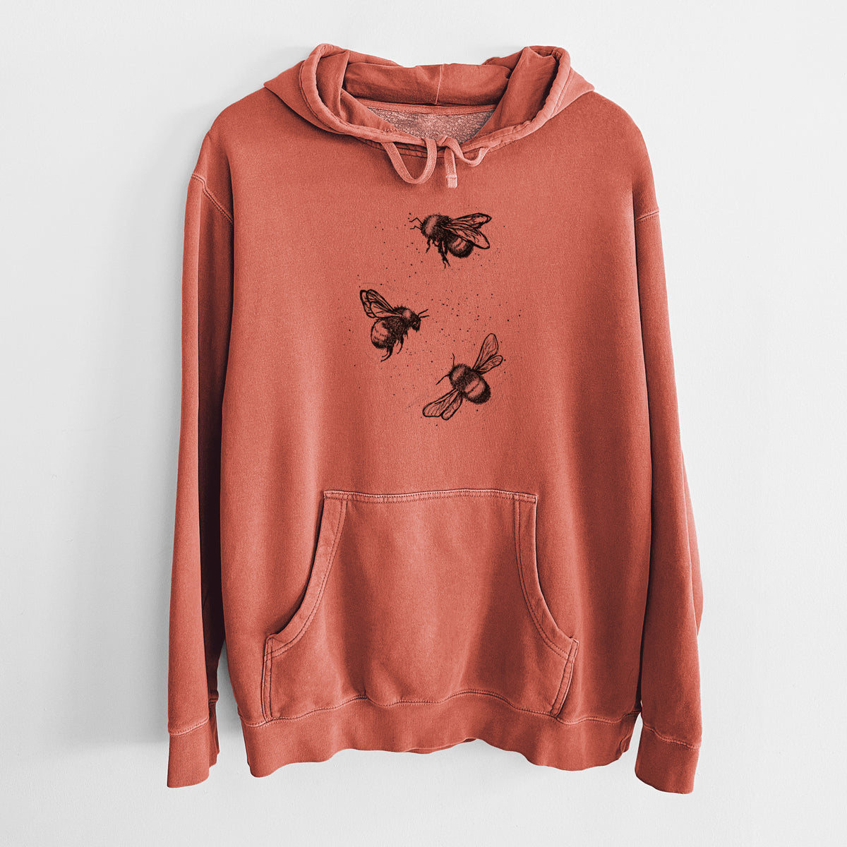Amber orange pigment dyed hoodie laid flat, printed with a black ink illustration of three bumble bees flying.