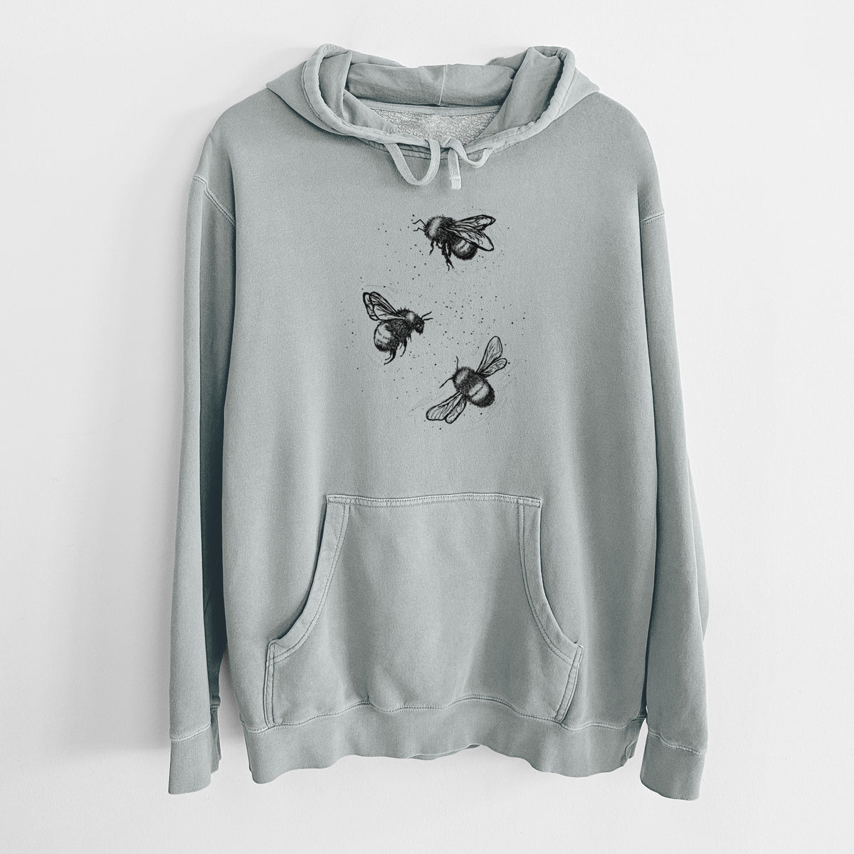 Sage green pigment dyed hoodie laid flat, printed with a black ink illustration of three bumble bees flying.