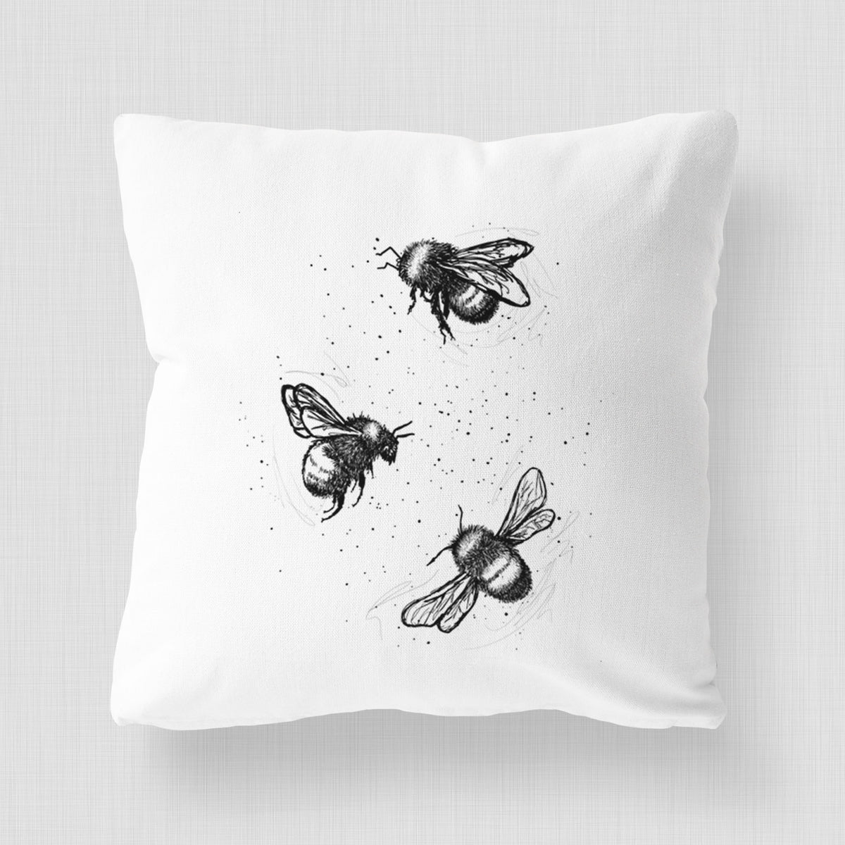 White pillow cover printed with a black ink illustration of three bumble bees flying.