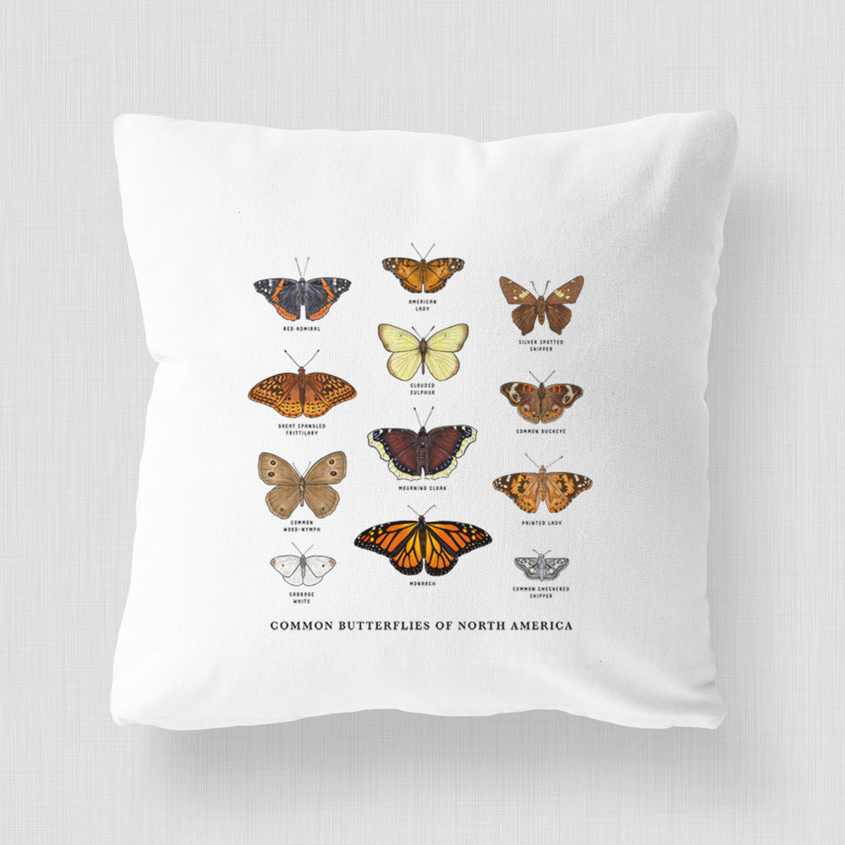 White pillow cover printed with a full-color chart of common butterflies of North America, each labeled with its species.