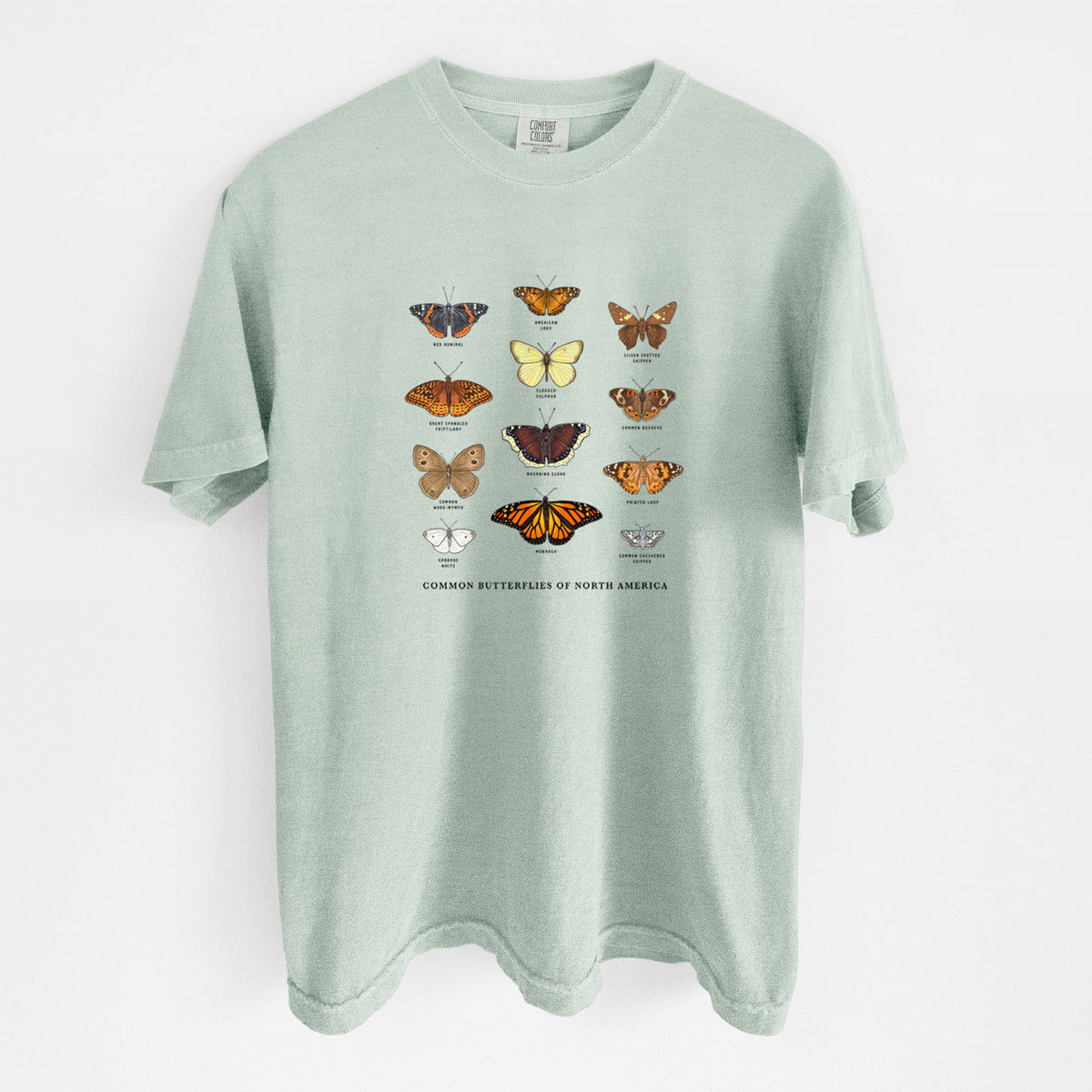 Bay green Comfort Colors t-shirt laid flat, printed with a full-color chart of common butterflies of North America, each labeled with its species.