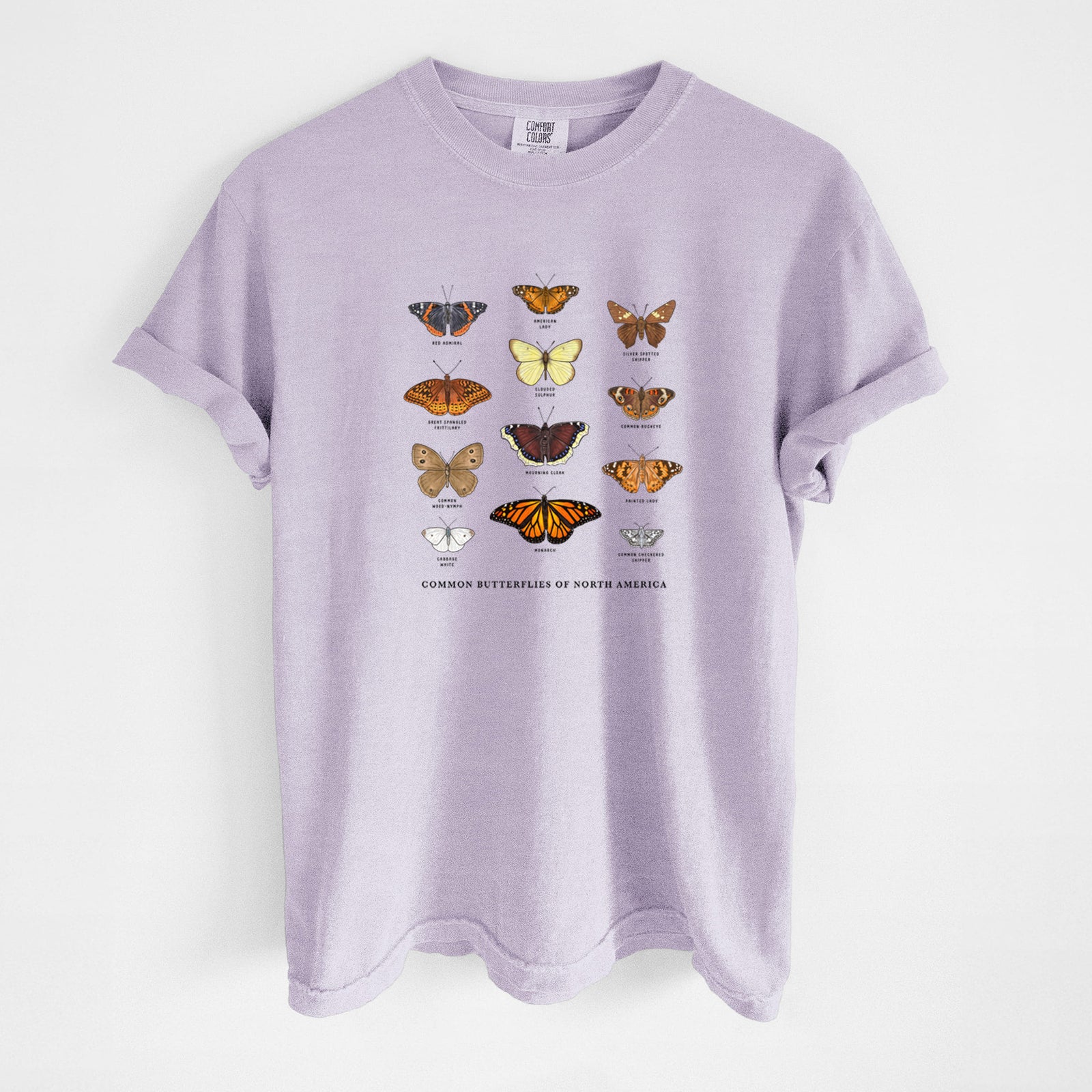 Orchid purple Comfort Colors t-shirt laid flat, printed with a full-color chart of common butterflies of North America, each labeled with its species.