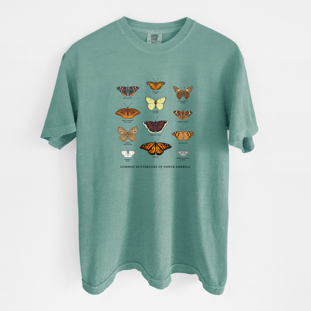Reef green Comfort Colors t-shirt laid flat, printed with a full-color chart of common butterflies of North America, each labeled with its species.