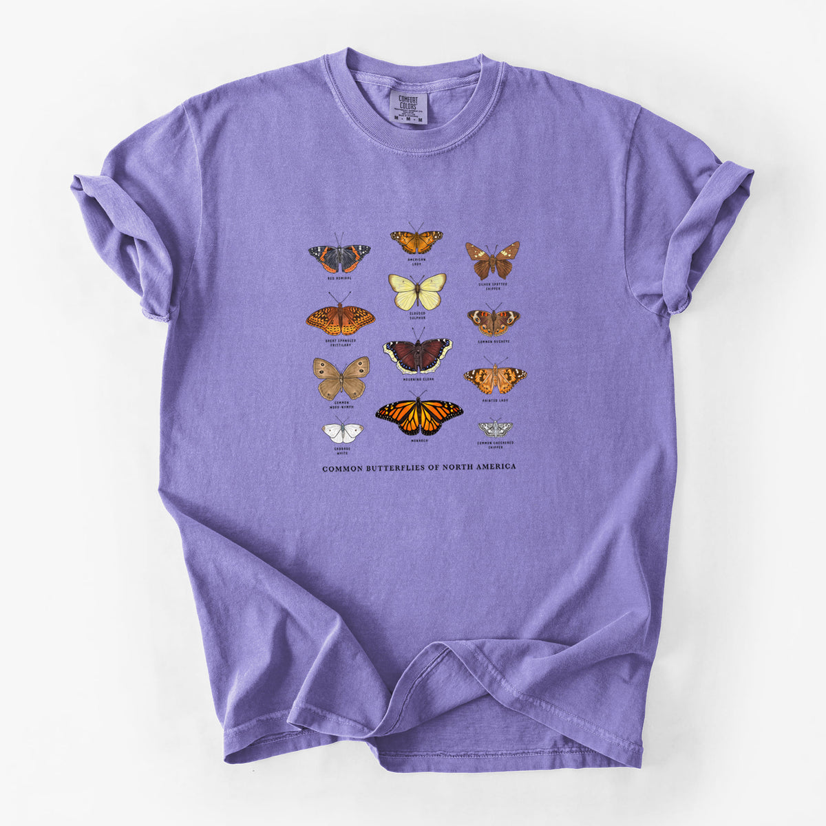 Violet purple Comfort Colors t-shirt laid flat, printed with a full-color chart of common butterflies of North America, each labeled with its species.