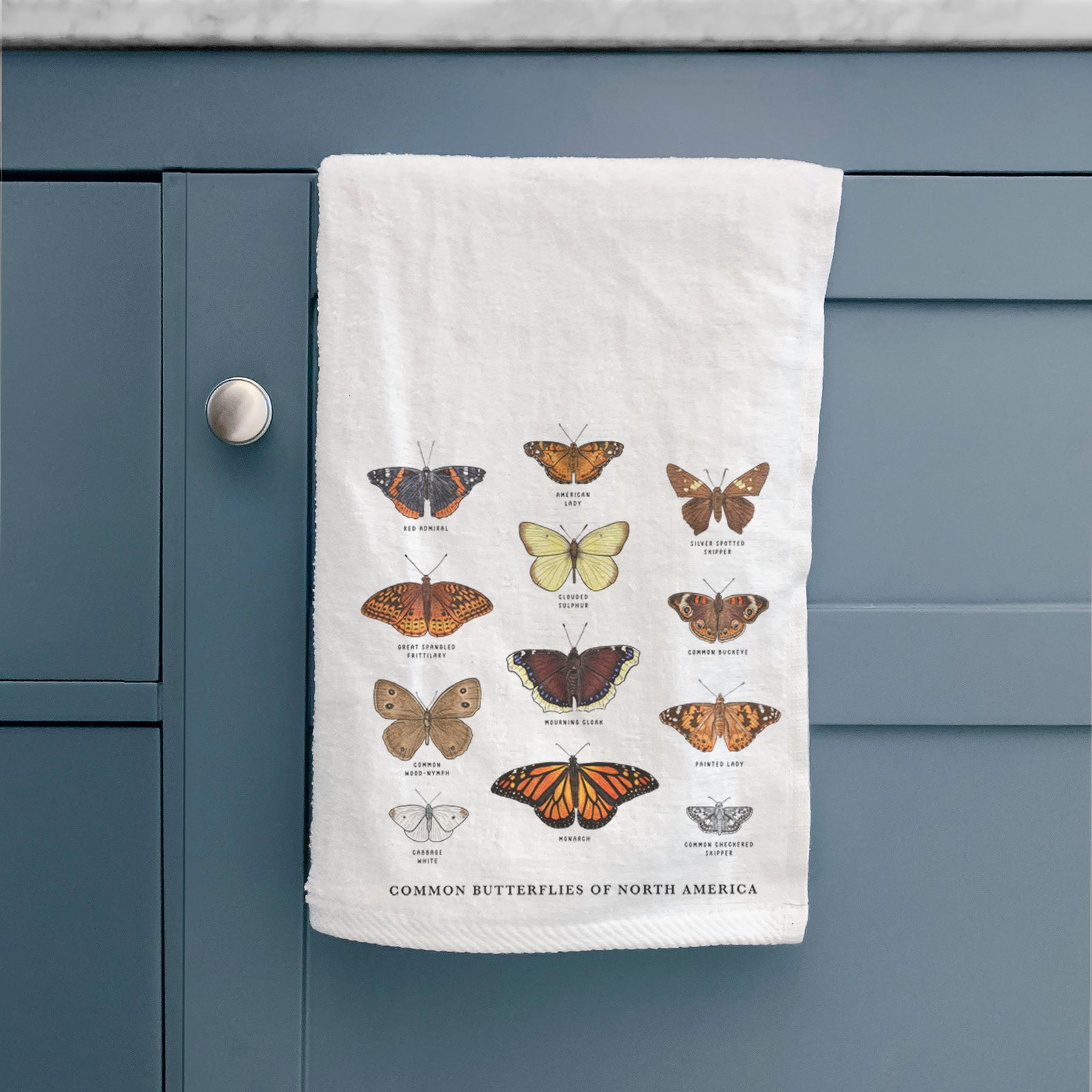 White hand towel printed with a full-color chart of common butterflies of North America, each labeled with its species.