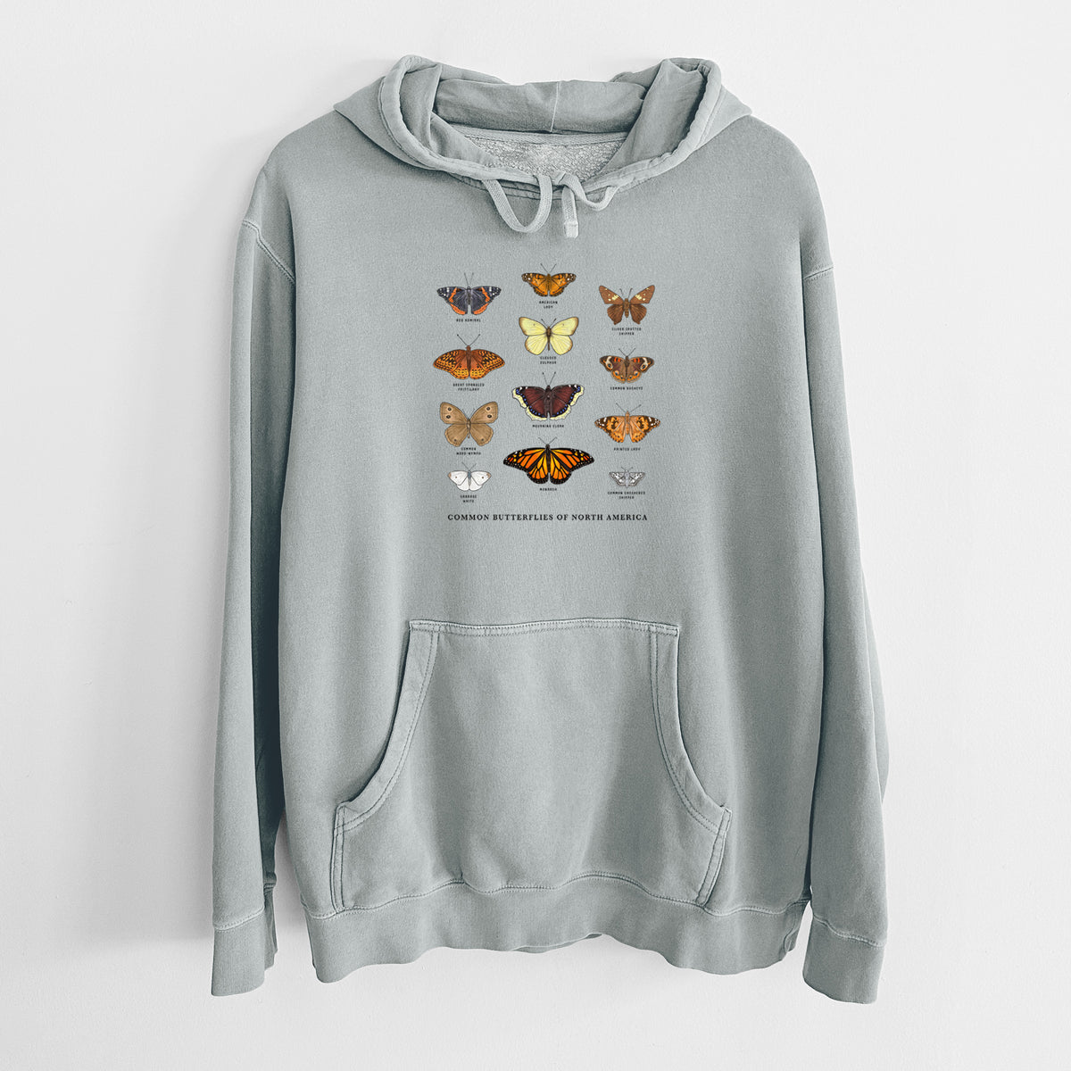Sage green pigment dyed hoodie laid flat, printed with a full-color chart of common butterflies of North America, each labeled with its species.