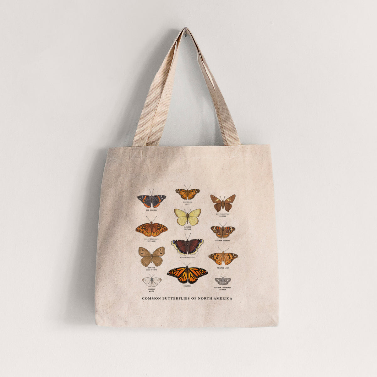 Natural canvas tote bag printed with a full-color chart of common butterflies of North America, each labeled with its species.