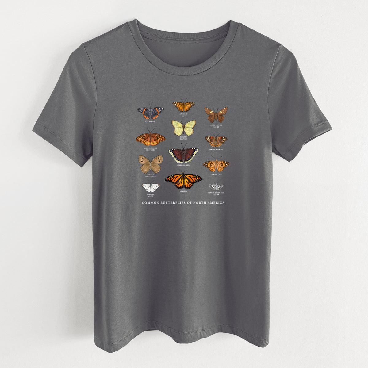 Asphalt women's relaxed fit cotton t-shirt laid flat, printed with a full-color chart of common butterflies of North America, each labeled with its species.