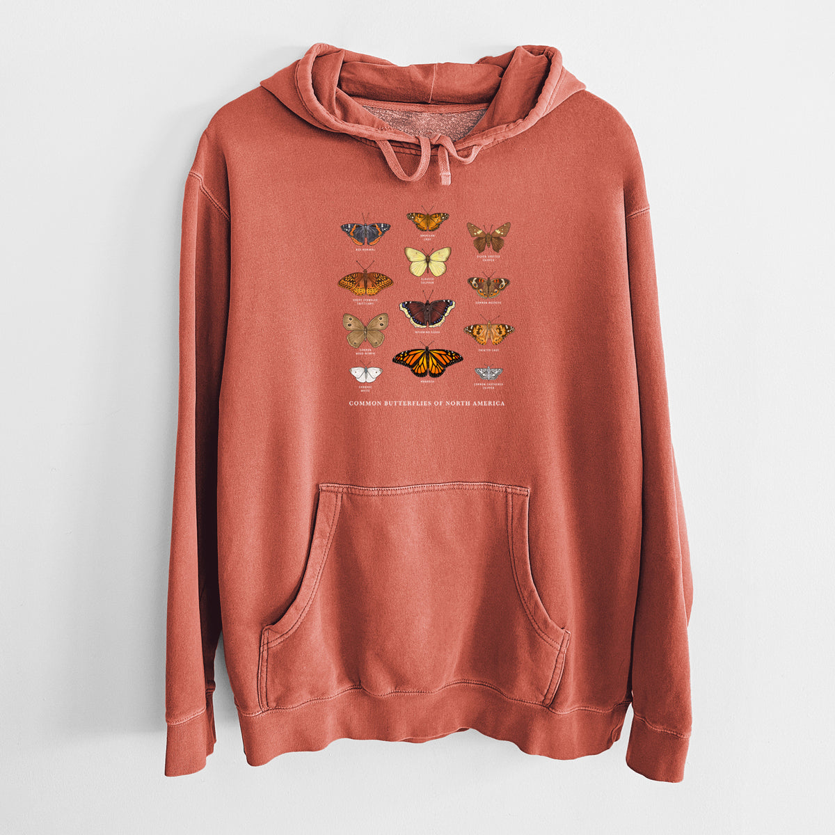 Amber orange pigment dyed hoodie laid flat, printed with a full-color chart of common butterflies of North America, each labeled with its species.