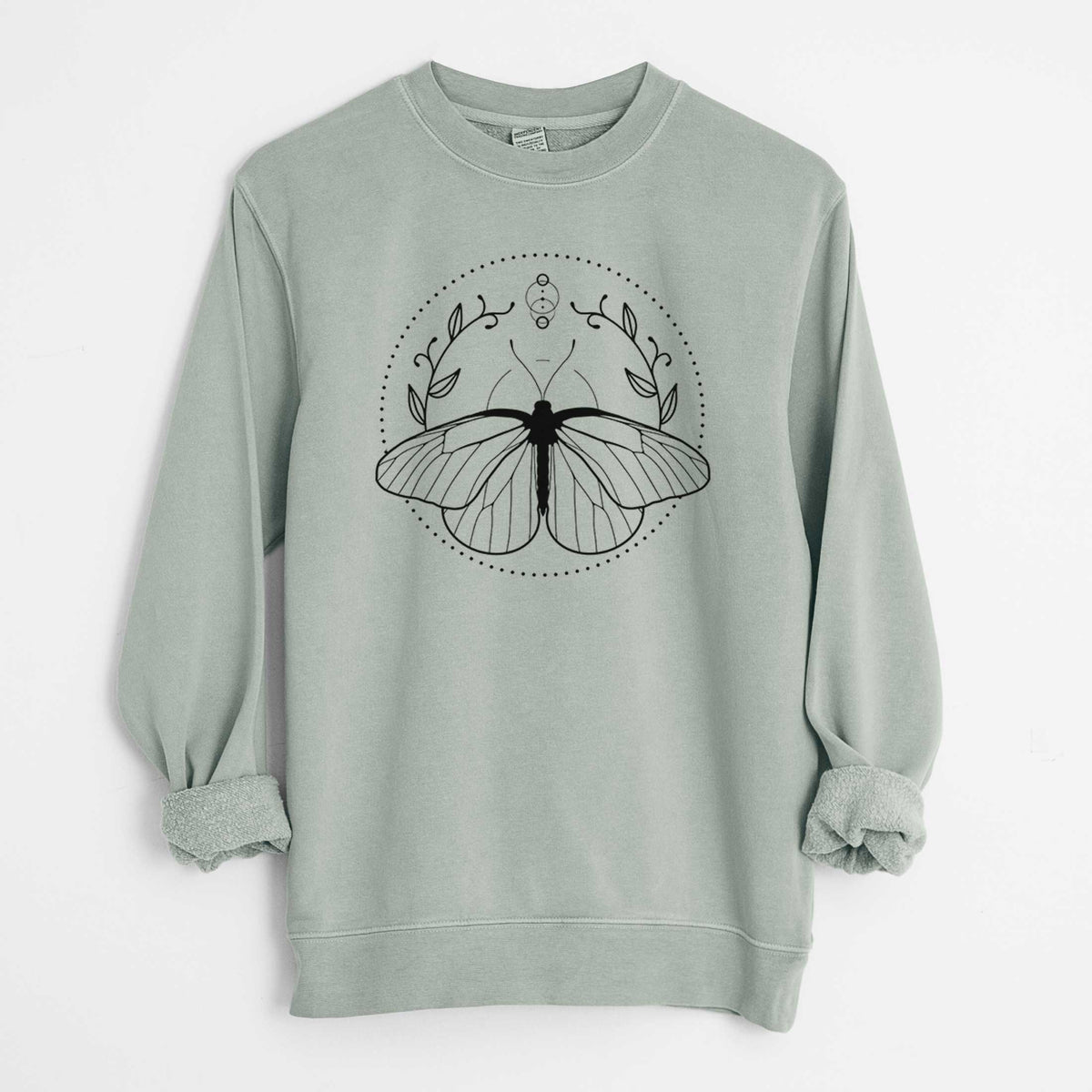 Sage green pigment dyed crewneck sweatshirt laid flat with the sleeves rolled, printed with a black ink butterfly inside a circle, framed by moon phases and leaves.