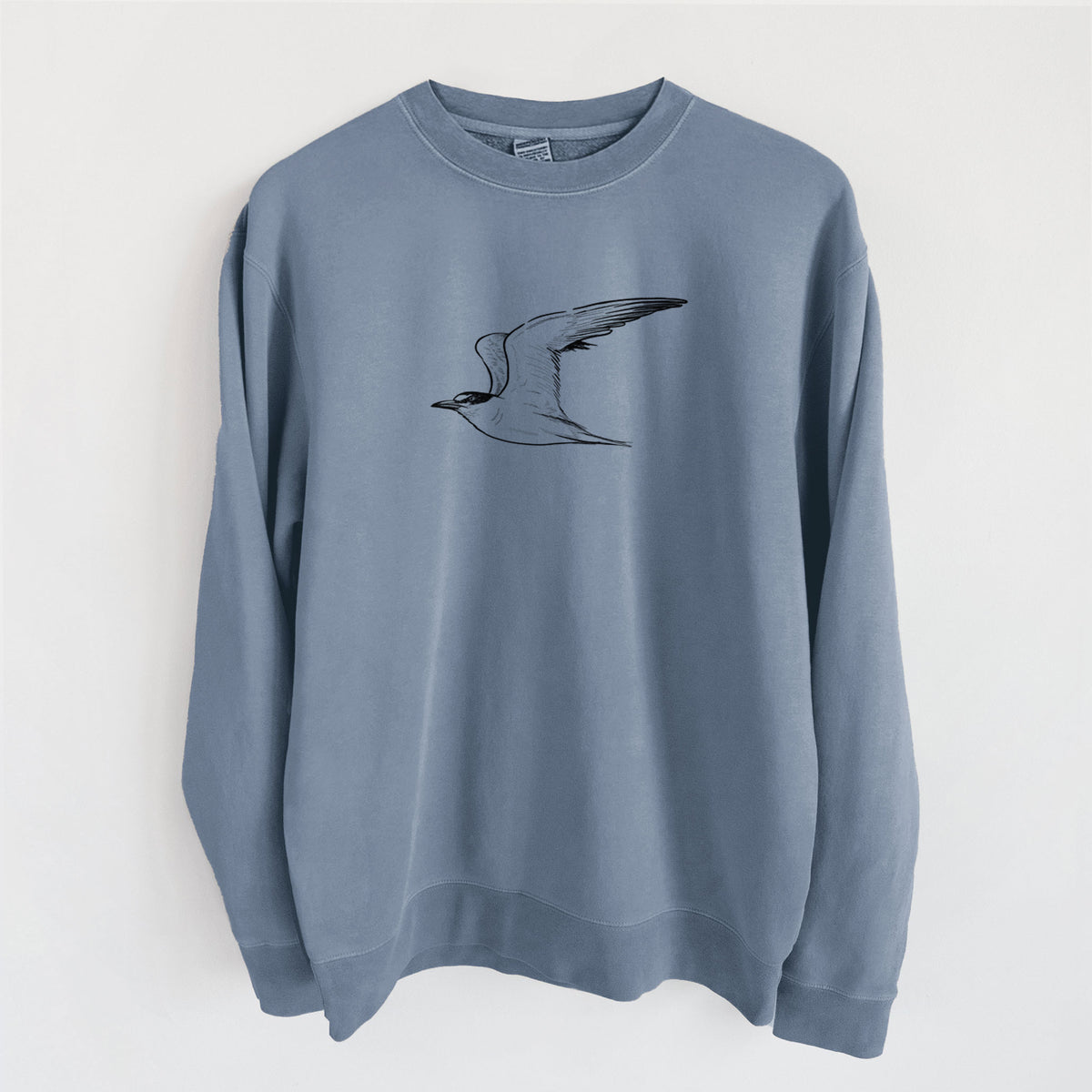 Slate blue pigment dyed crewneck sweatshirt laid flat, printed with a black ink illustration of a California least tern in flight.