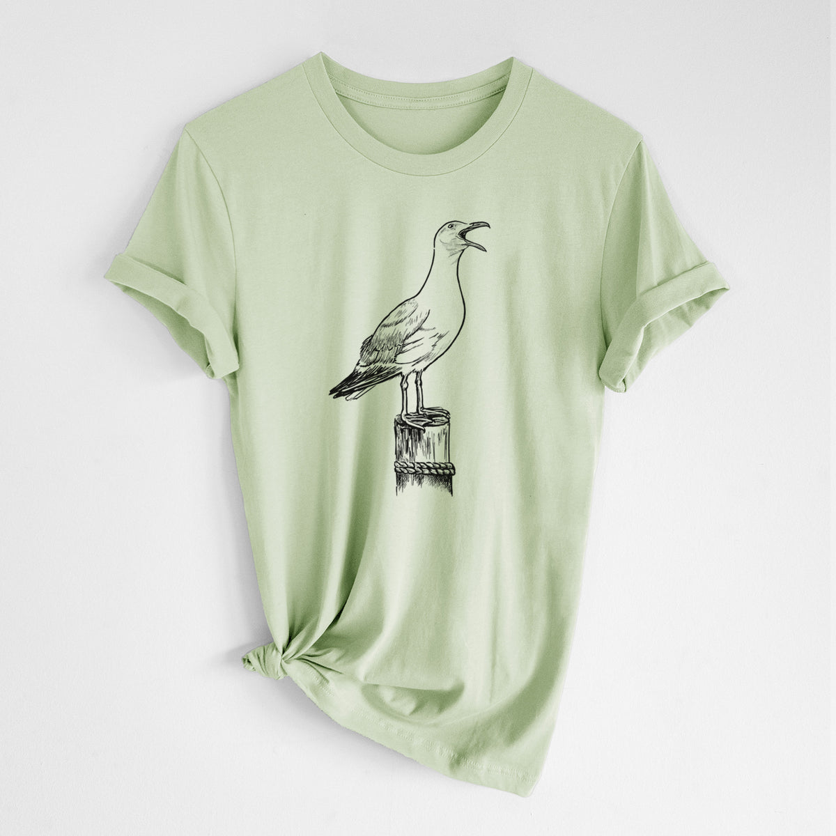Spring green lightweight cotton t-shirt laid flat with the sleeves rolled, printed with a black ink illustration of a California gull calling from a wooden post.