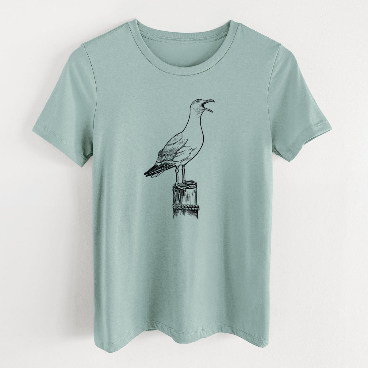 Dusty blue women's relaxed fit cotton t-shirt laid flat, printed with a black ink illustration of a California gull calling from a wooden post.