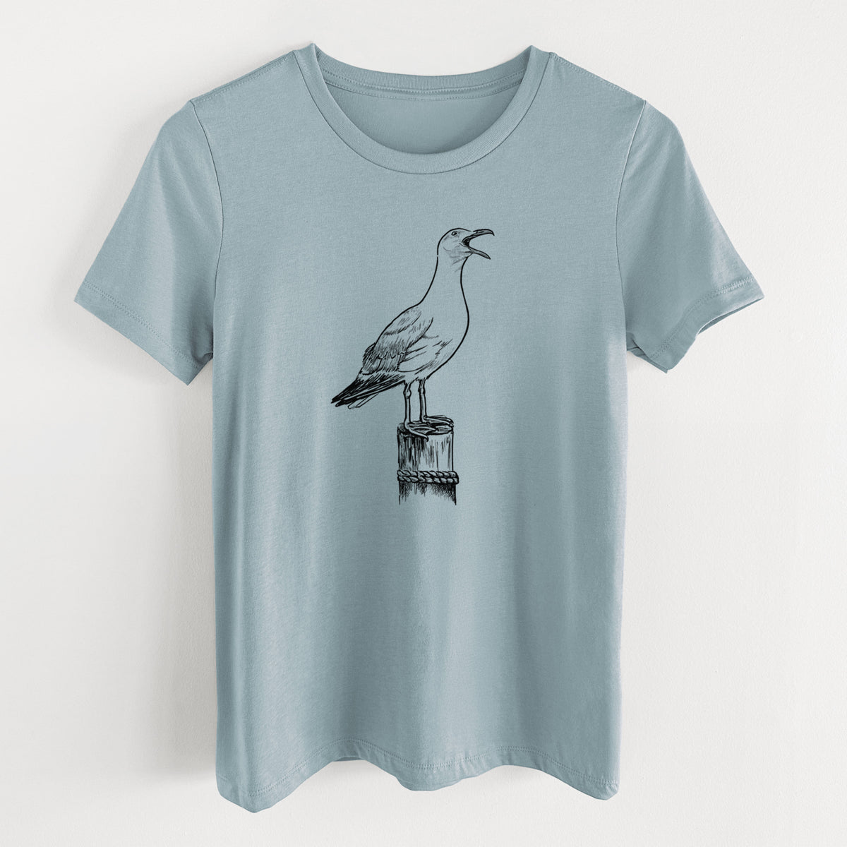 Vintage denim women's relaxed fit cotton t-shirt laid flat, printed with a black ink illustration of a California gull calling from a wooden post.