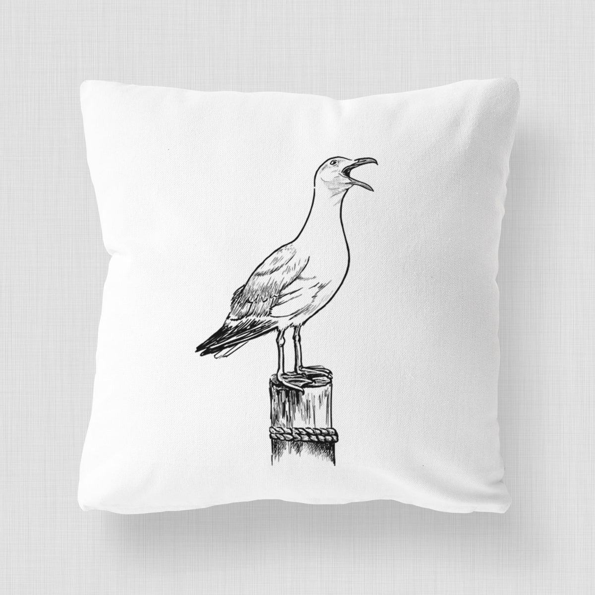White pillow cover printed with a black ink illustration of a California gull calling from a wooden post.