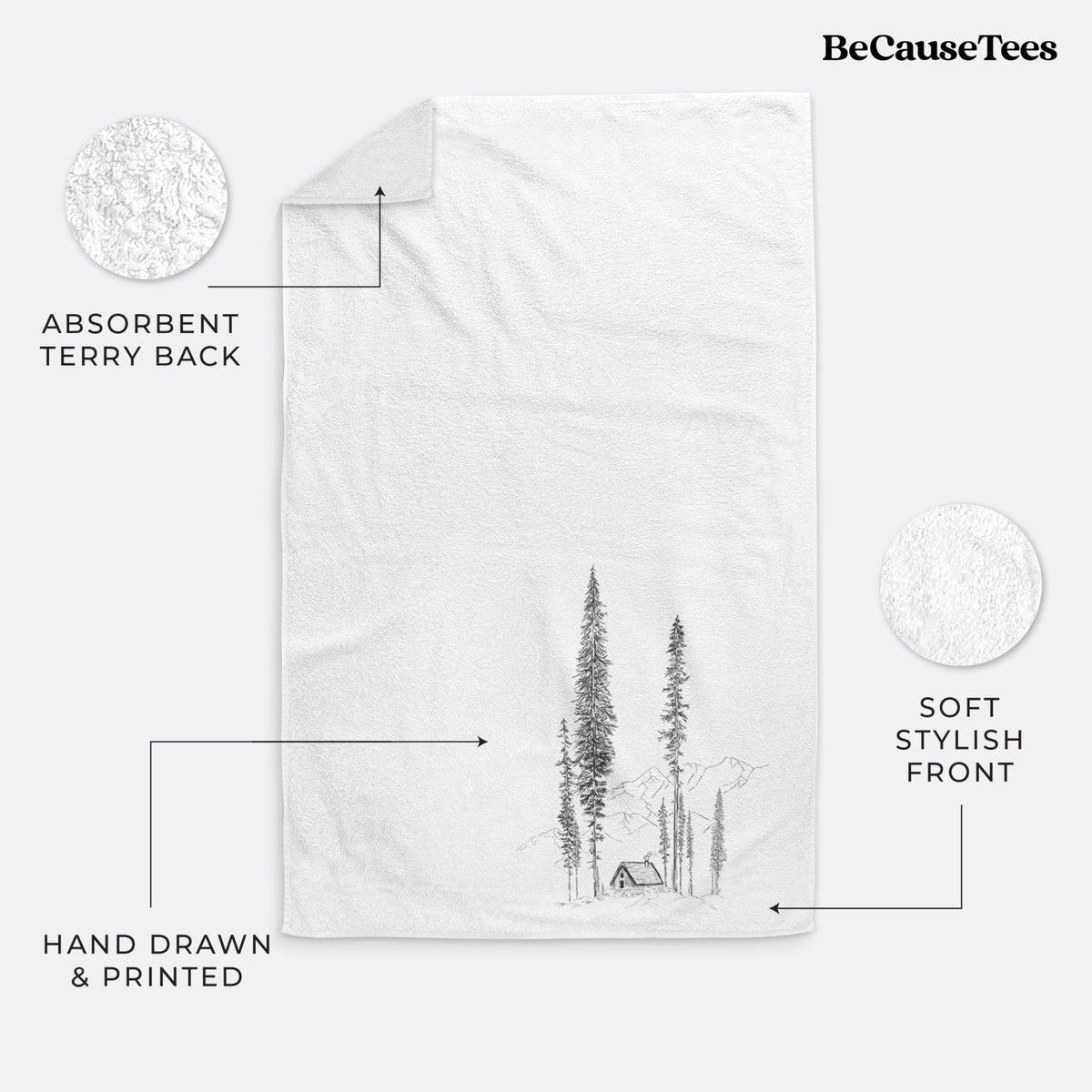 White hand towel printed with a black ink illustration of a small cabin nestled beneath towering pine trees.