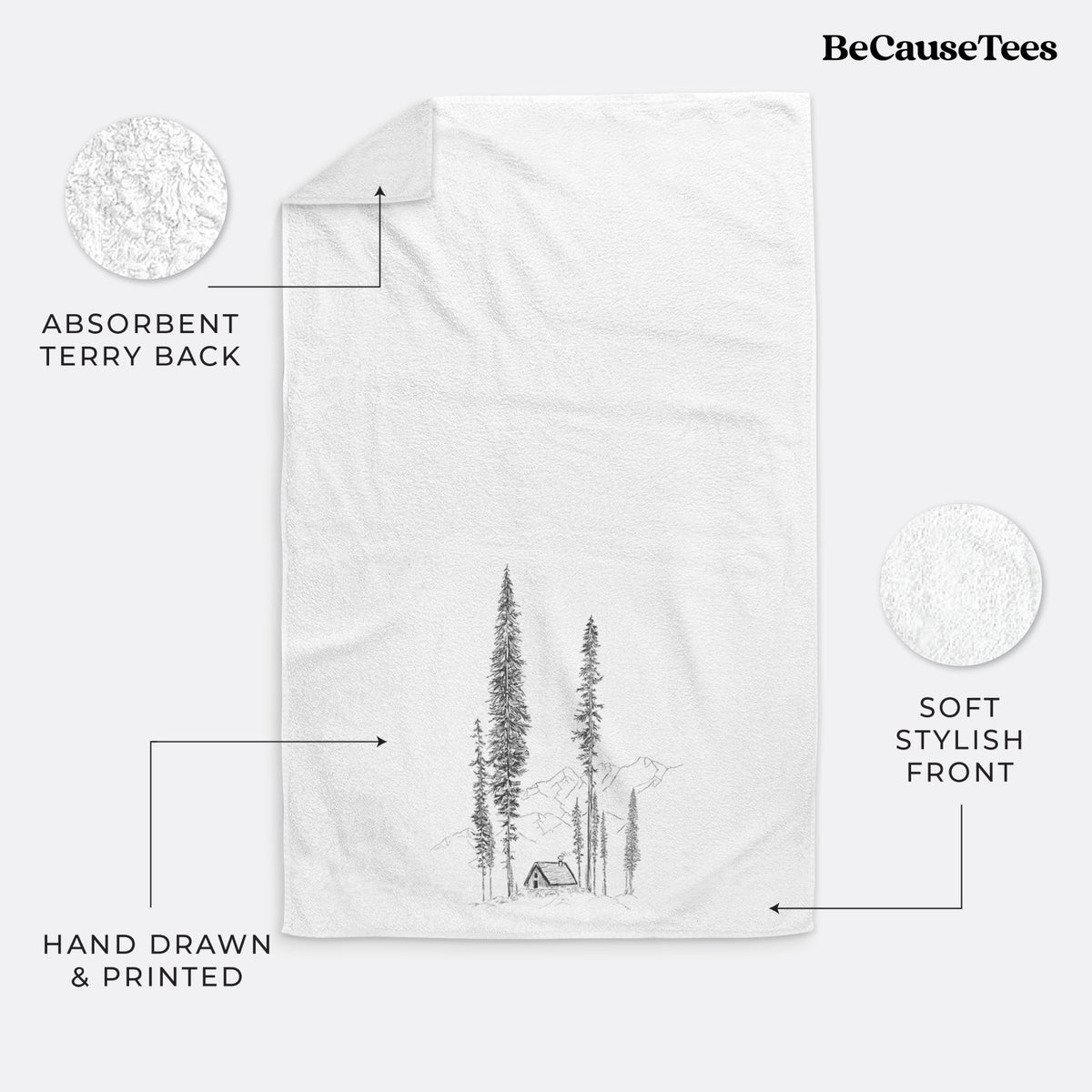 White hand towel printed with a black ink illustration of a small cabin nestled beneath towering pine trees.