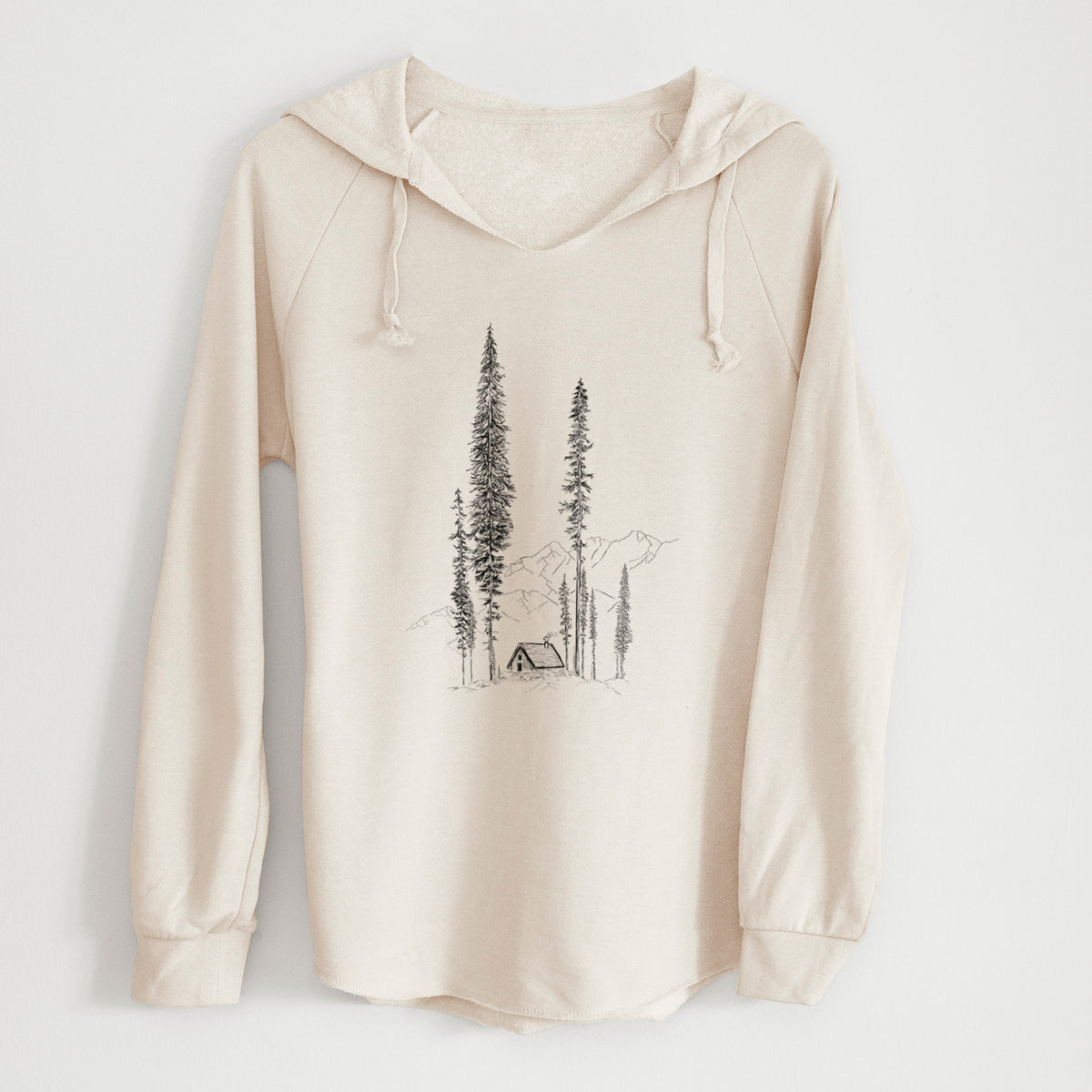 Bone cream women's Cali Wave hooded sweatshirt laid flat, printed with a black ink illustration of a small cabin nestled beneath towering pine trees.