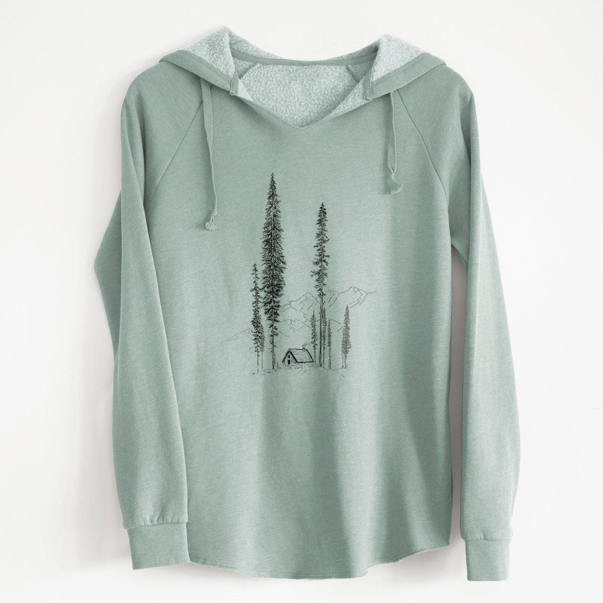 Sage green women's Cali Wave hooded sweatshirt laid flat, printed with a black ink illustration of a small cabin nestled beneath towering pine trees.