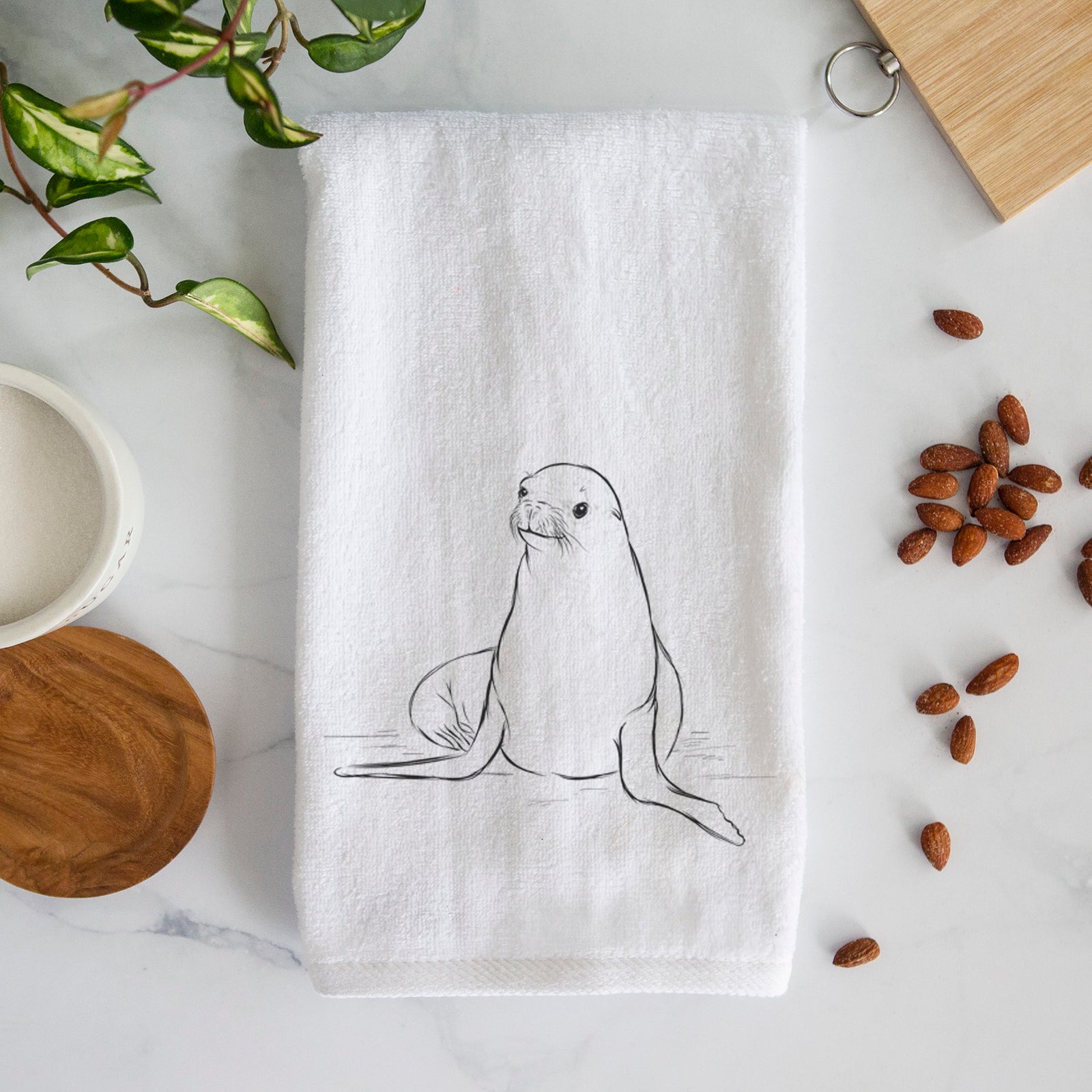 White hand towel printed with a black ink illustration of a California sea lion sitting upright.