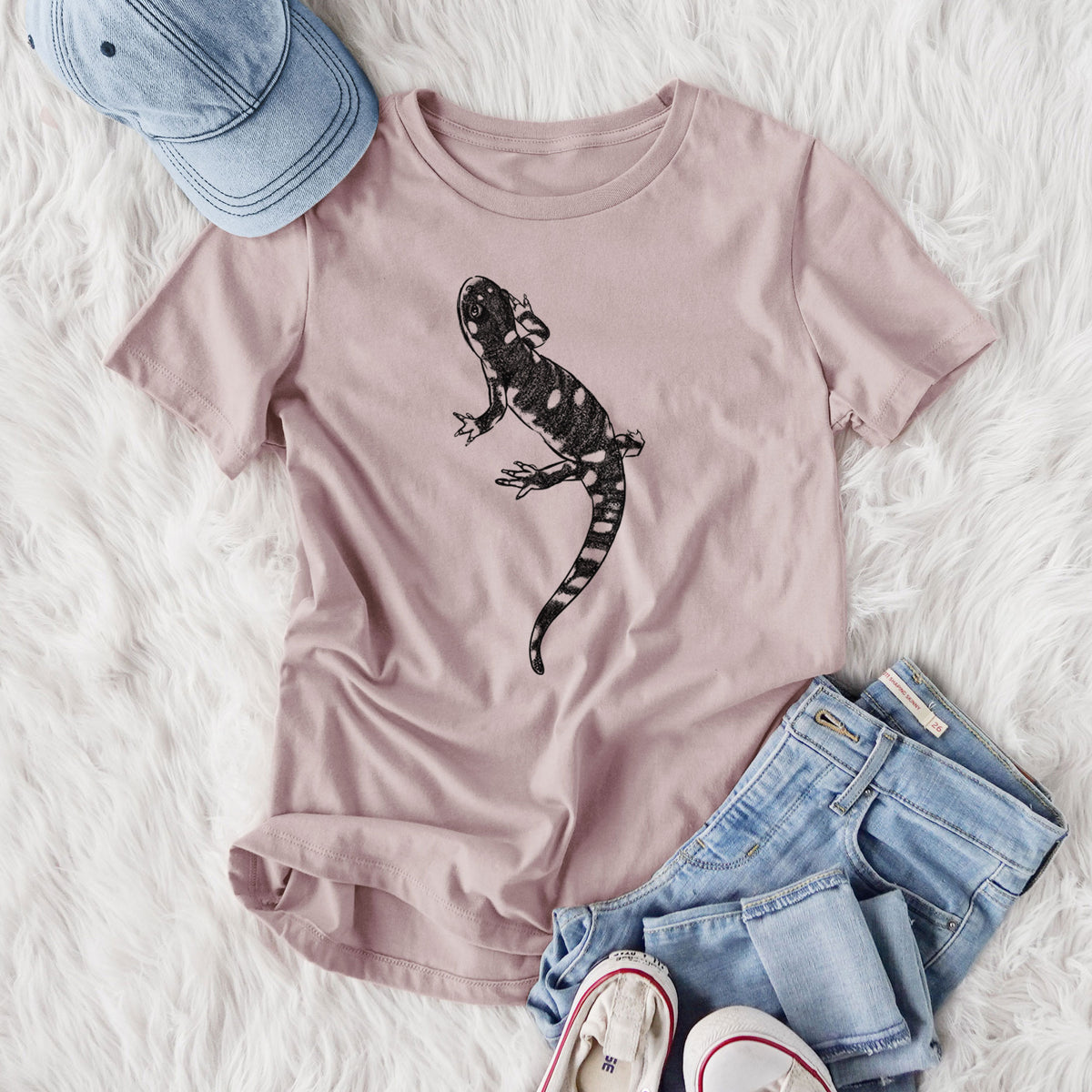 Women's relaxed fit cotton t-shirt printed with a detailed black ink illustration of a spotted California tiger salamander, styled flat on a white faux fur rug with jeans.