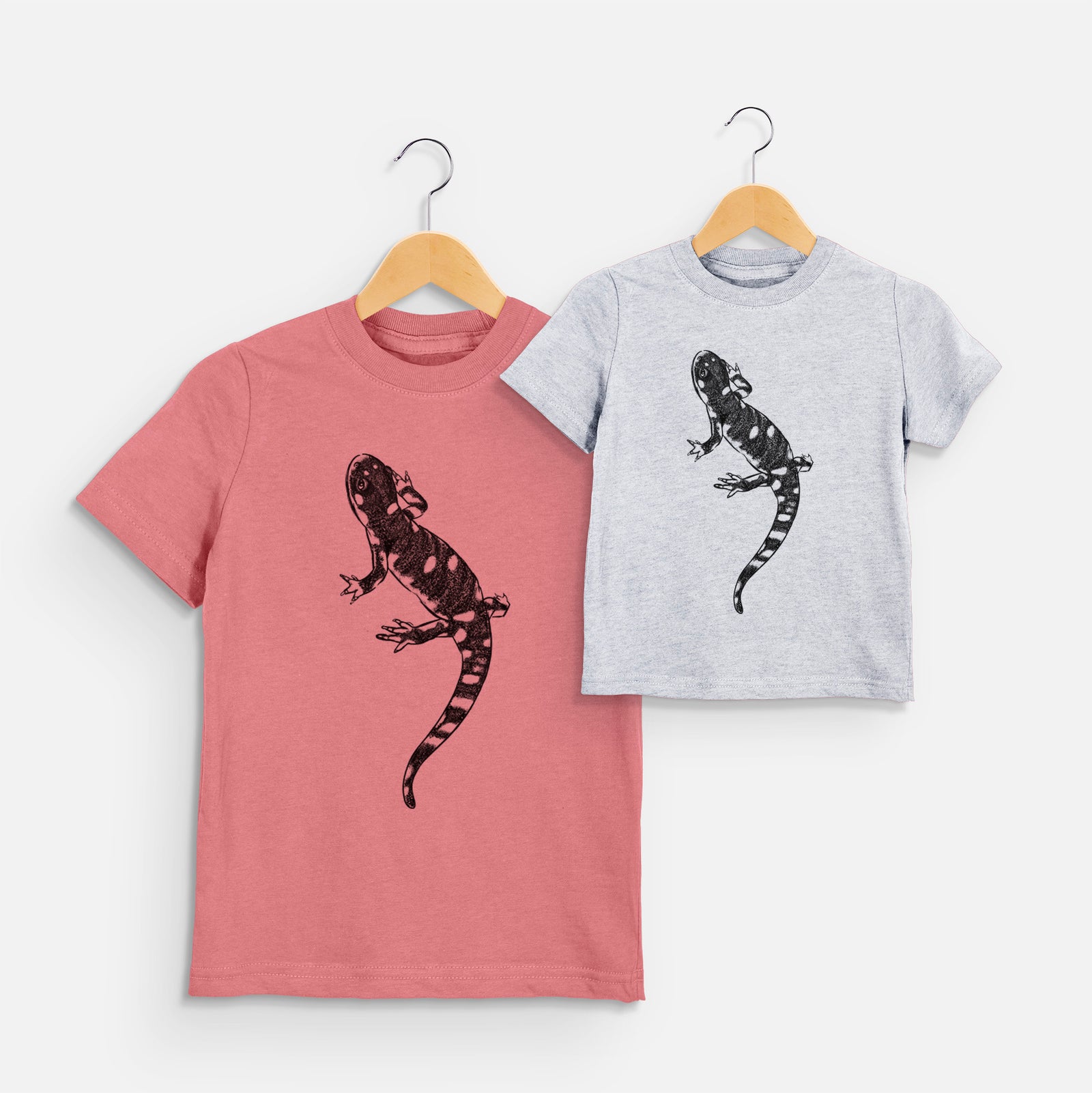 Two youth t-shirts in different colors on hangers, printed with a detailed black ink illustration of a spotted California tiger salamander.