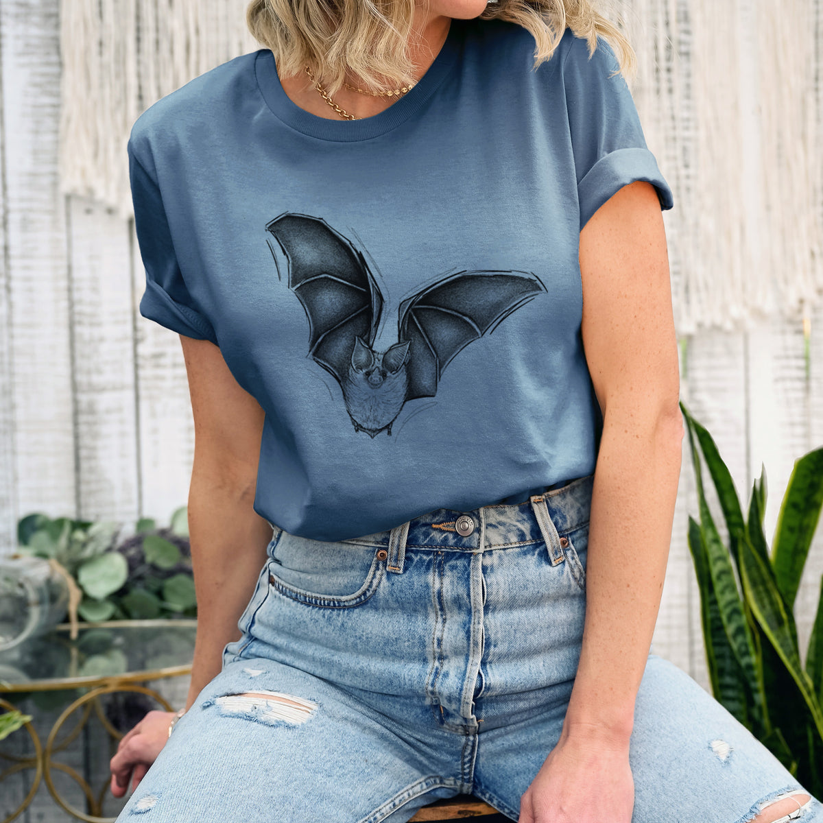 Woman wearing a steel blue lightweight cotton t-shirt printed with a detailed black ink illustration of a California leaf-nosed bat in flight.