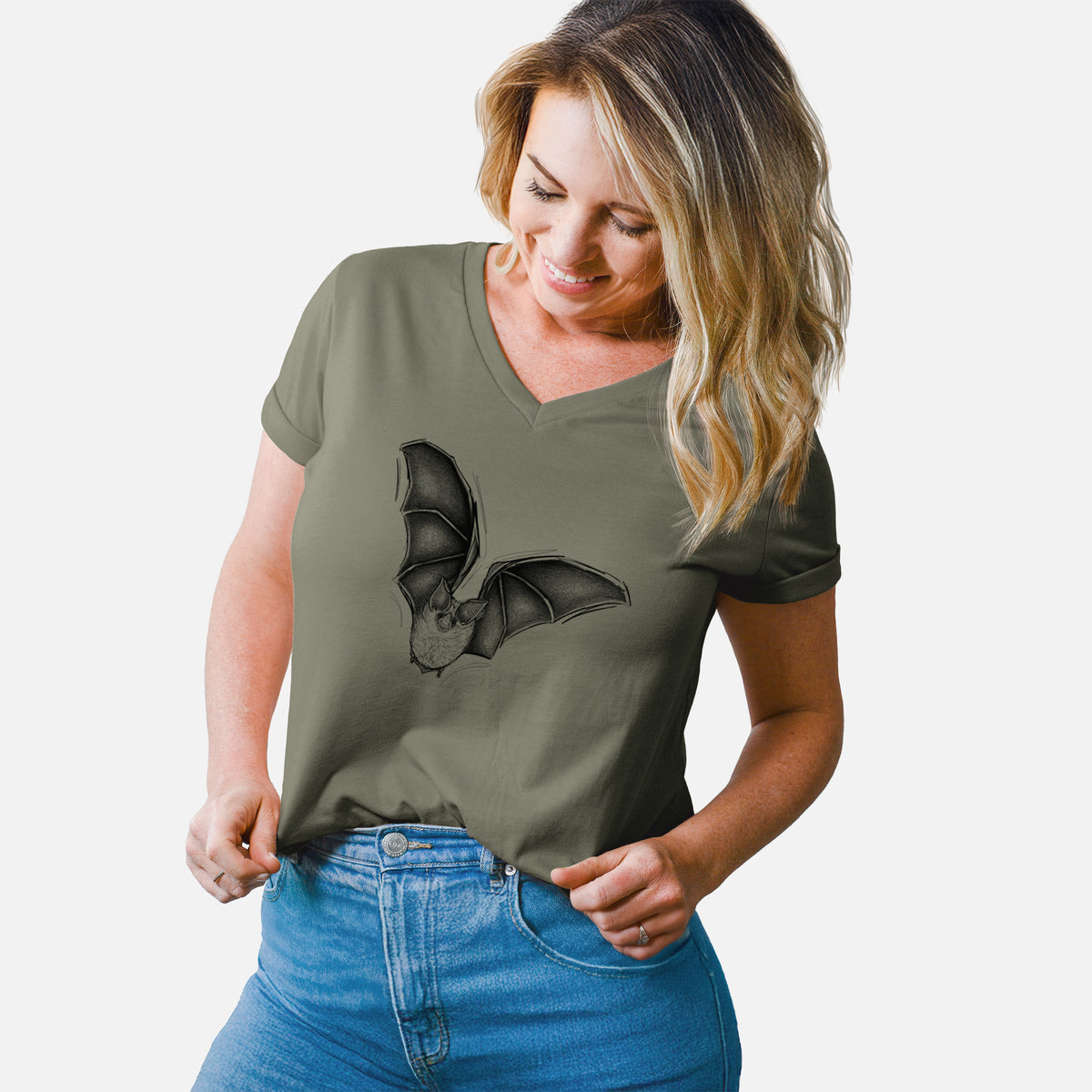 Woman wearing a military green women's relaxed fit cotton V-neck t-shirt printed with a detailed black ink illustration of a California leaf-nosed bat in flight.