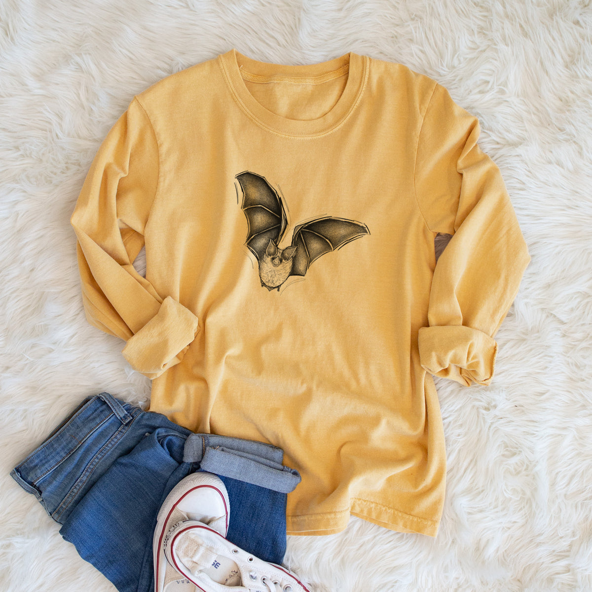 Golden wheat yellow Comfort Colors long sleeve shirt printed with a detailed black ink illustration of a California leaf-nosed bat in flight, shown in a lifestyle photo.