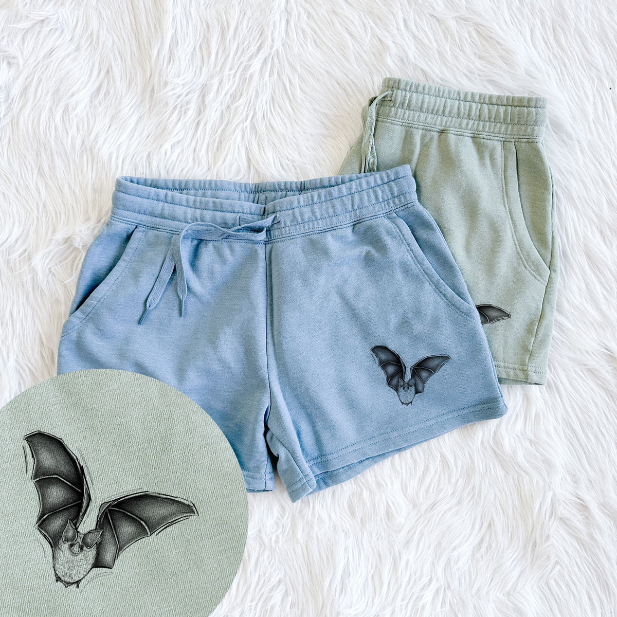 Two pairs of Cali Wave shorts in different colors printed with a detailed black ink illustration of a California leaf-nosed bat in flight, with a close-up of the print.