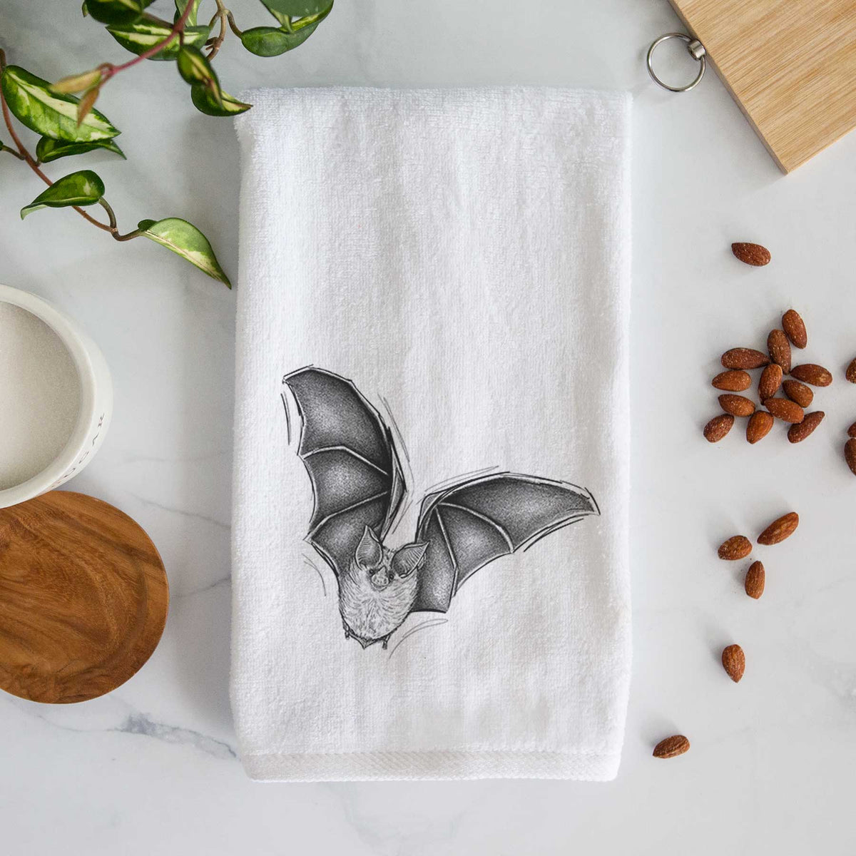 White hand towel printed with a detailed black ink illustration of a California leaf-nosed bat in flight.