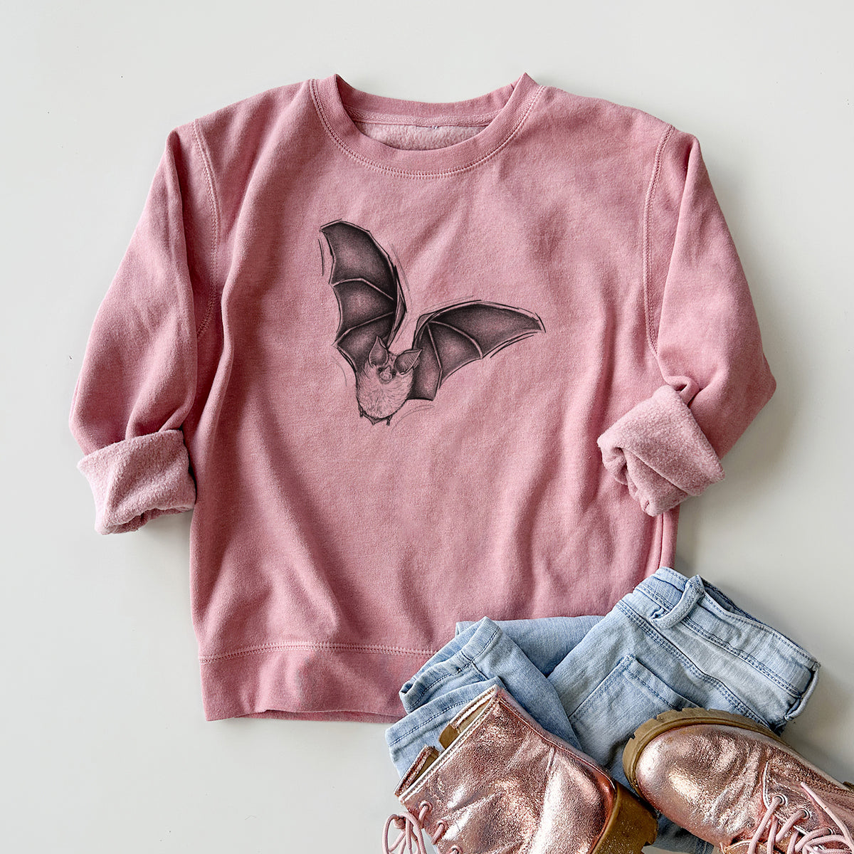 Youth crewneck sweatshirt printed with a detailed black ink illustration of a California leaf-nosed bat in flight, styled flat with jeans and boots.