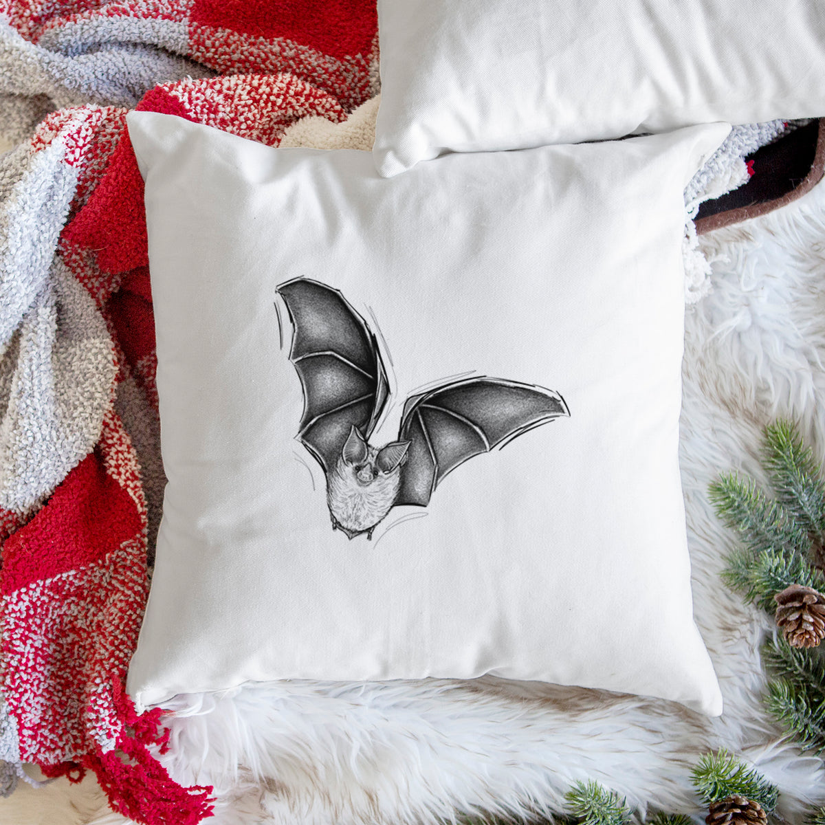 White pillow cover printed with a detailed black ink illustration of a California leaf-nosed bat in flight, on a woven chair.