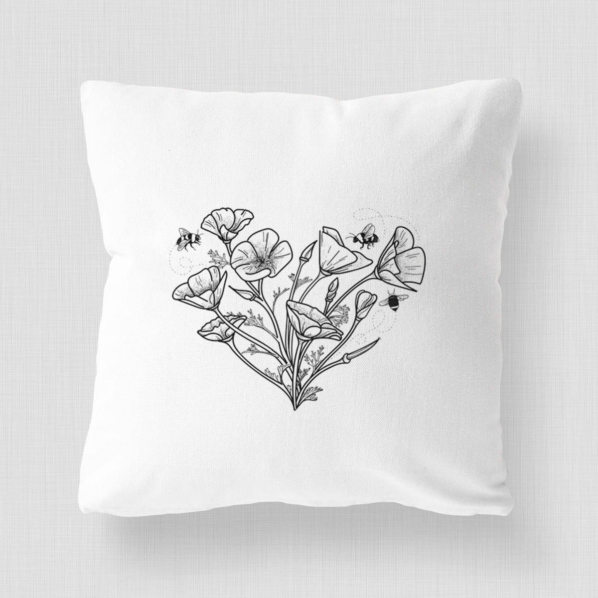 White pillow cover printed with a black ink line drawing of California poppies arranged in a heart shape, with small bees.