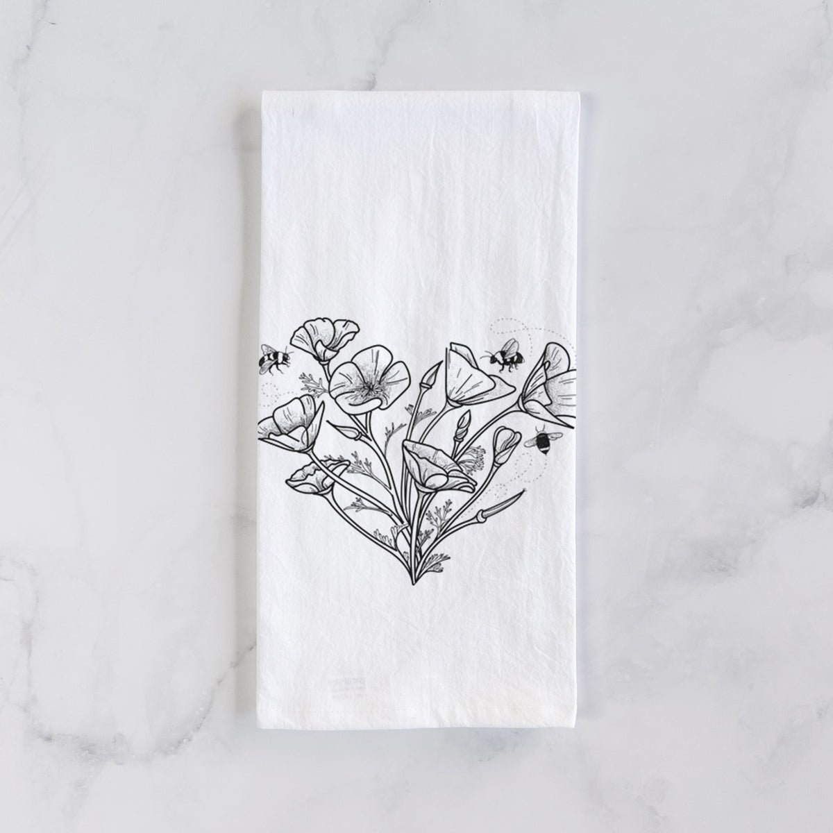 White cotton tea towel laid flat on marble, printed with a black ink line drawing of California poppies arranged in a heart shape, with small bees.