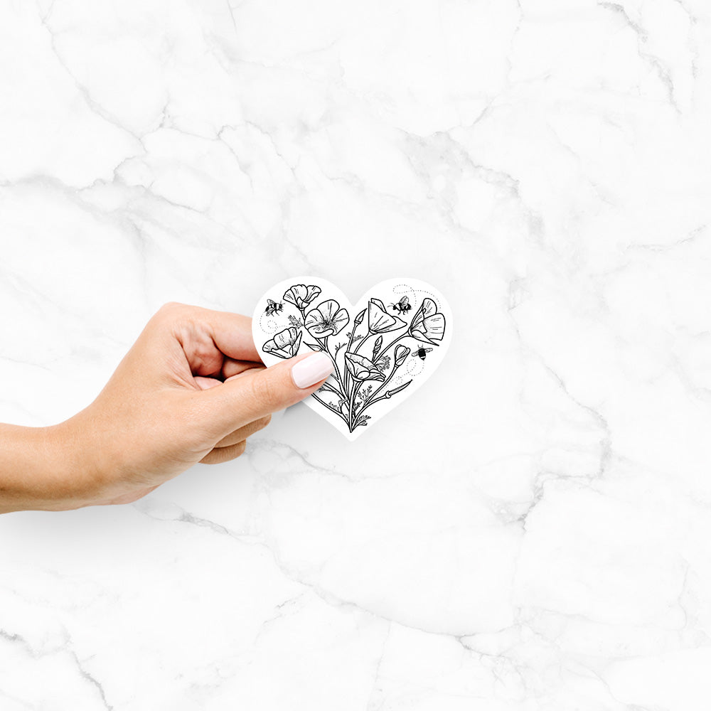 Hand holding a 4 inch vinyl decal of a black ink line drawing of California poppies arranged in a heart shape, with small bees.