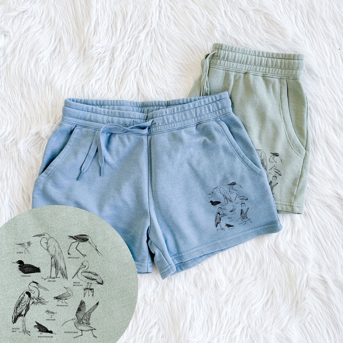 Two pairs of Cali Wave shorts in different colors printed with a chart of black ink California shorebirds, including herons, egrets, avocets and sandpipers, with a close-up of the print.