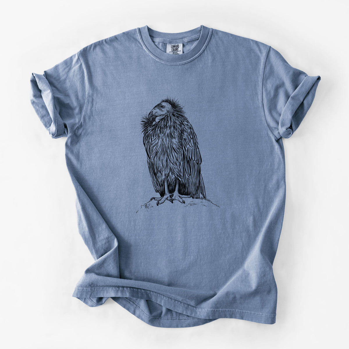 Blue jean Comfort Colors t-shirt laid flat, printed with a detailed black ink illustration of a California condor perched with folded wings.