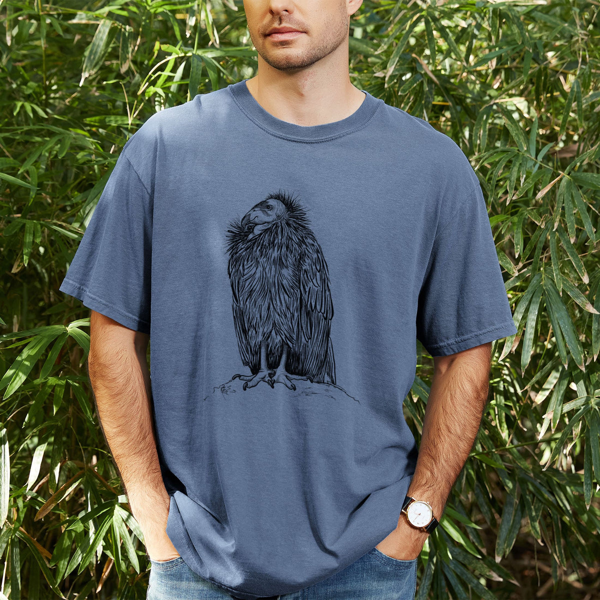 Man wearing a Comfort Colors t-shirt printed with a detailed black ink illustration of a California condor perched with folded wings, outdoors.