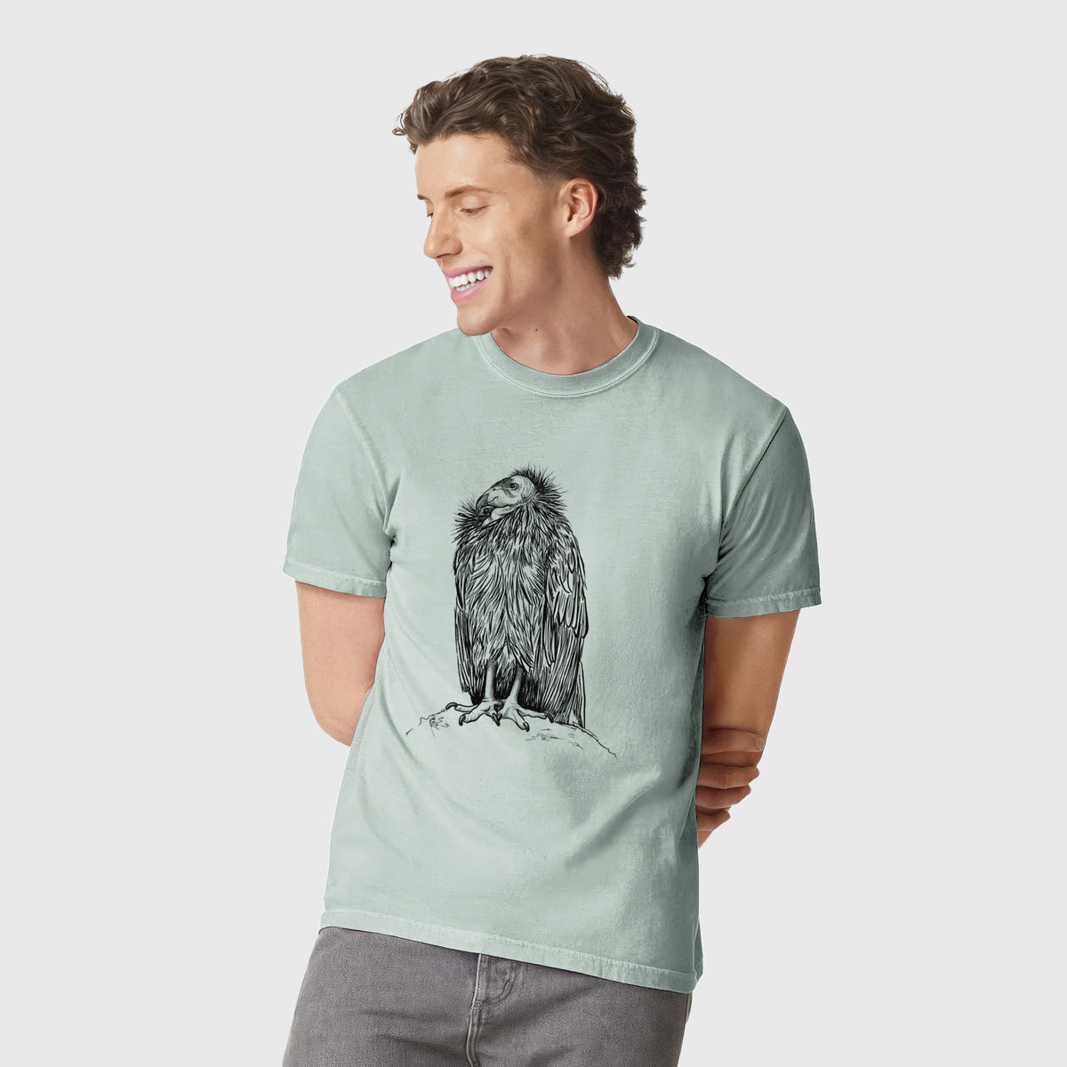 Man wearing a Comfort Colors t-shirt printed with a detailed black ink illustration of a California condor perched with folded wings.