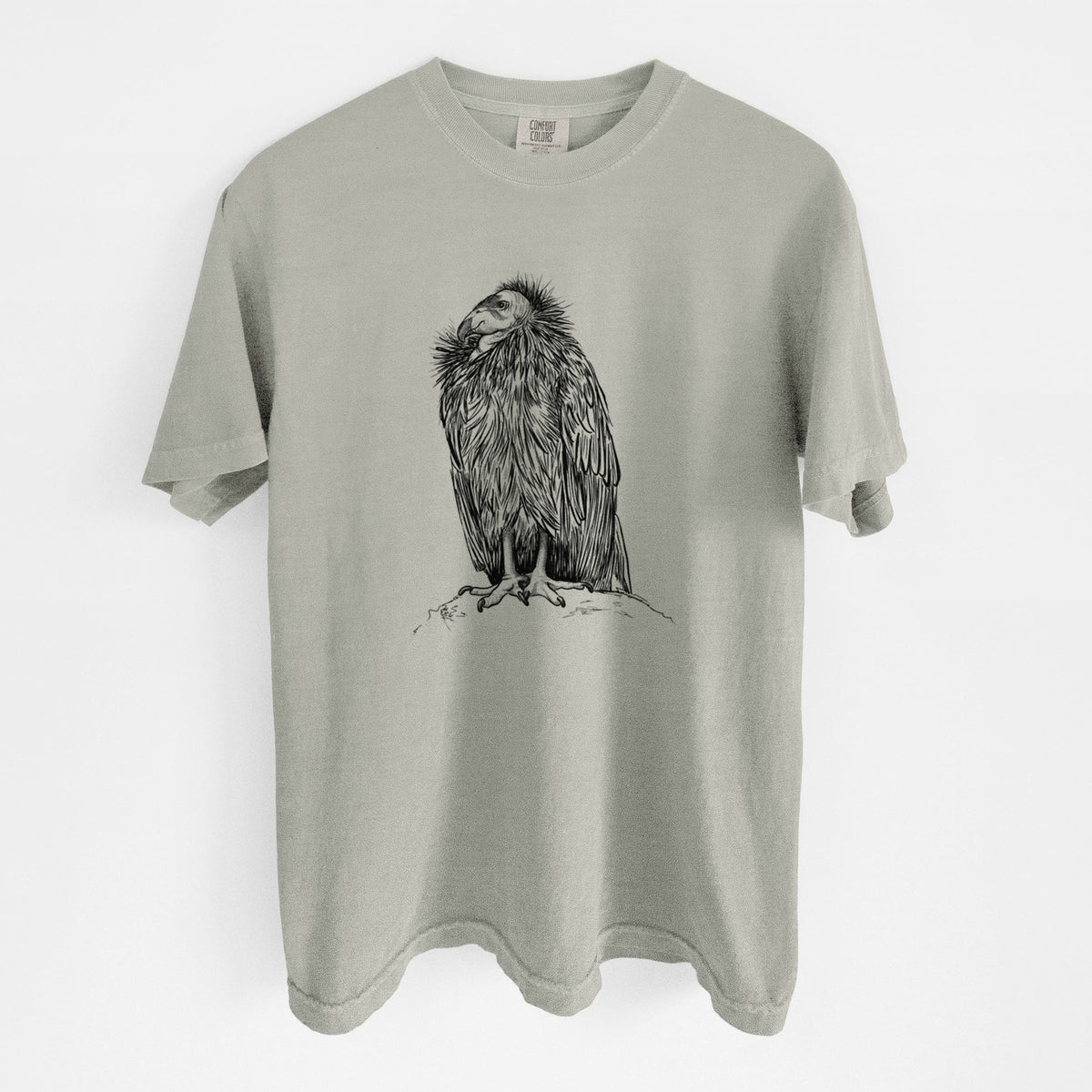 Sandstone beige Comfort Colors t-shirt laid flat, printed with a detailed black ink illustration of a California condor perched with folded wings.