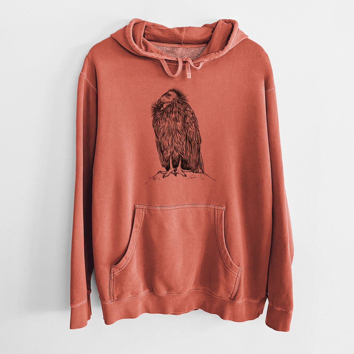 Amber orange pigment dyed hoodie laid flat, printed with a detailed black ink illustration of a California condor perched with folded wings.