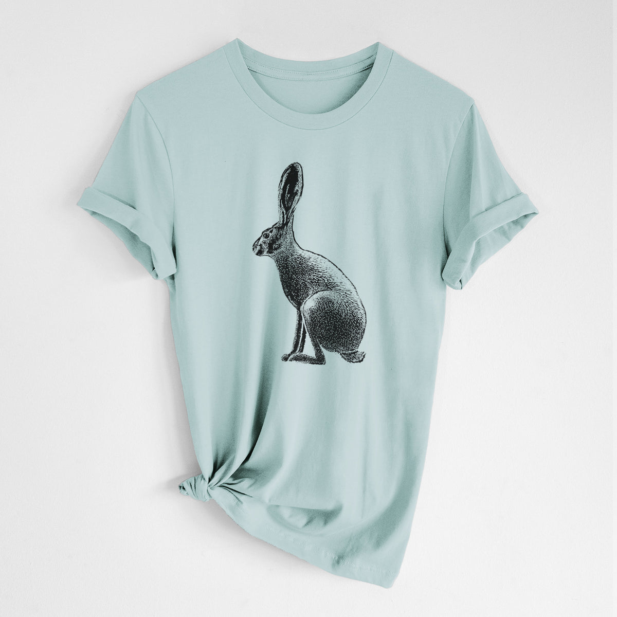 Dusty blue lightweight cotton t-shirt laid flat with the sleeves rolled, printed with a detailed black ink illustration of a black-tailed jackrabbit sitting in profile with tall ears.
