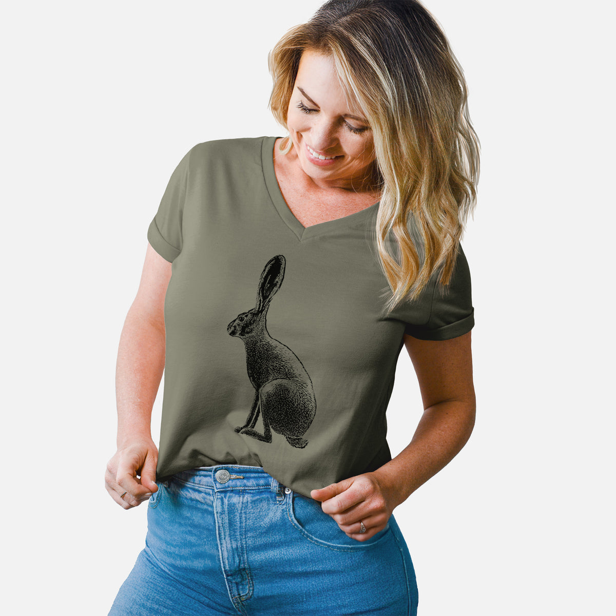 Woman wearing a military green women's relaxed fit cotton V-neck t-shirt printed with a detailed black ink illustration of a black-tailed jackrabbit sitting in profile with tall ears.