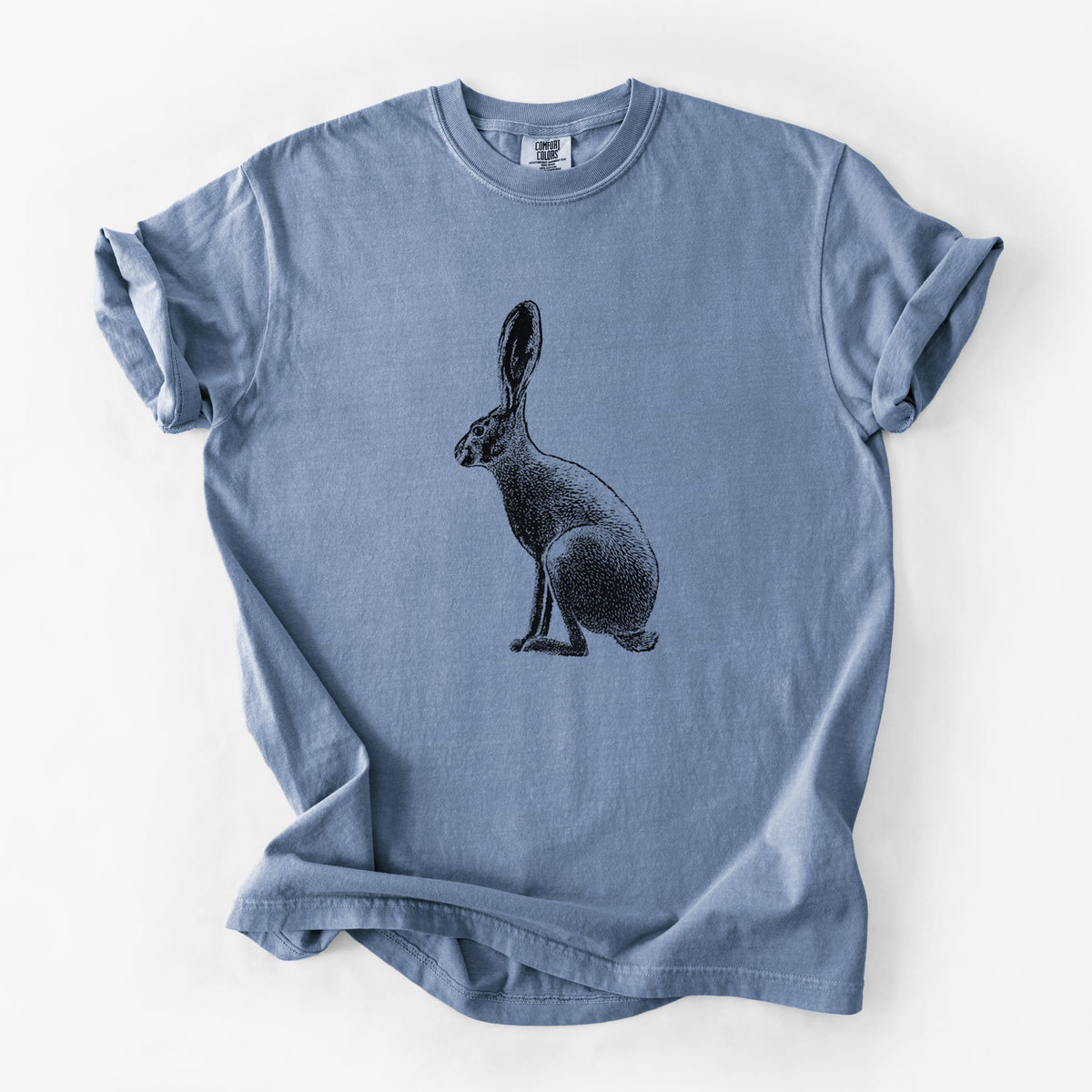 Blue jean Comfort Colors t-shirt laid flat, printed with a detailed black ink illustration of a black-tailed jackrabbit sitting in profile with tall ears.